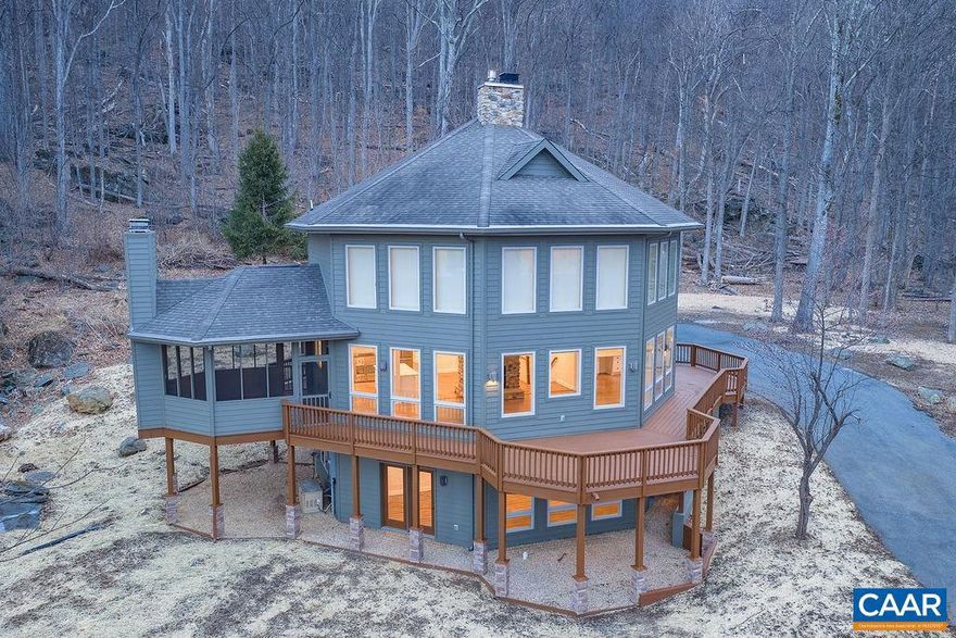 Near the highest elevation in Stoney Creek, this newly renovated mountaintop retreat captures panoramic Rockfish Valley views and exceptional privacy on 2.74 acres backing to nearly 11,000 acres of Wintergreen Resort land. A dramatic wall of south-facing windows fills the home with natural light and frames the mountain landscape, while hardwood floors, a striking stone pass-through fireplace, and an open kitchen create a warm, connected living space. Outdoor living is the showpiece, with a rare wraparound deck, walkout rooftop patio with hot tub hookup, and a screened-in porch with its own wood-burning fireplace for year-round enjoyment. The landscape is enhanced by dramatic natural boulders that add character and a true mountain-lodge feel. The kitchen features a coordinated Forno stainless steel appliance package, including a 36-inch French-door range, convection microwave, refrigerator, and dishwasher. The upper-level primary suite includes a walk-in closet and en-suite bath, while the terrace level offers two bedrooms, a full bath, and a second living area for guests or flexible use.,Quartz Counter,White Cabinets,Wood Cabinets,Exterior Fireplace,Fireplace in Living Room