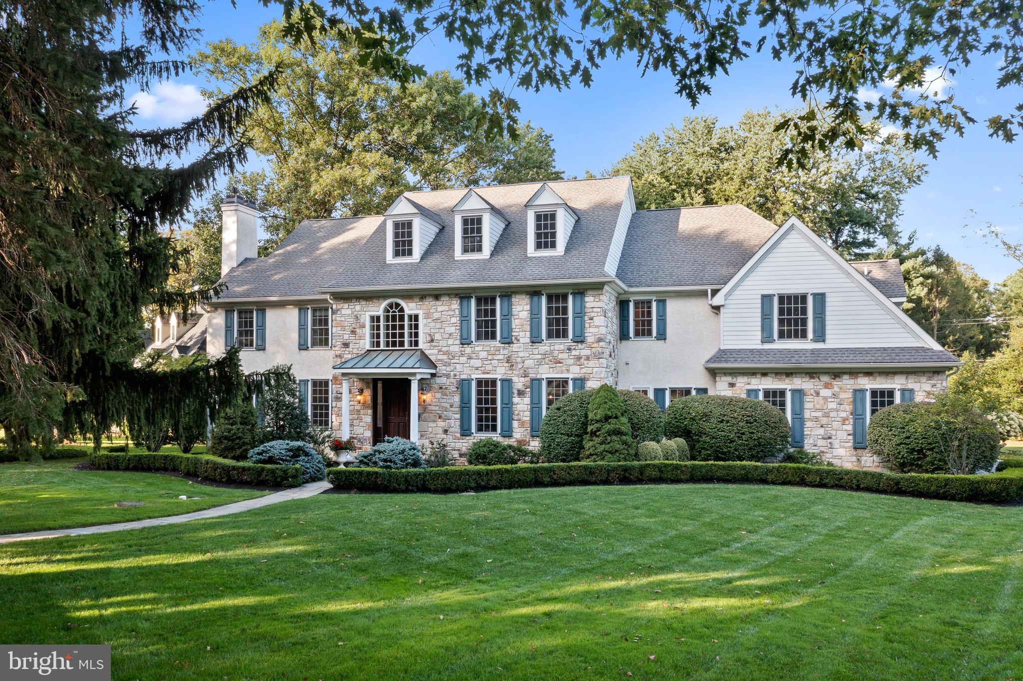An expertly crafted stone manor home, boasting beautiful stonework, a grand open floor plan, and high-end finishes that combine to make this home all that it is. Perfectly situated on nearly an acre of land in a prestigious Gladwyne neighborhood, offering immaculate views of the Philadelphia Country Club’s golf course. This exquisite estate stands grandly amid lush landscaping with specimen trees including a beautiful magnolia tree, vibrant hydrangea, and a handsome yew hedge surrounding the property creating a private and stately setting. A flagstone walkway leads to a welcoming, covered entrance. Greeting you inside is an impressive 2-story reception hall with gorgeous hardwood floors throughout the main level, a turned staircase, & a Palladian window that brightens the ambience. Tasteful moldings abound in the formal living room and dining room adding sophistication to each space. The family room features soaring ceilings, a wood burning fireplace, and a large window that displays the beautiful greenery surrounding the home. The open flow between the kitchen, breakfast room & family room keeps everyone connected & extends to the rear flagstone patio via glass-paneled doors. The updated gourmet kitchen is a chef’s dream with a large center island that provides barstool seating, crisp white cabinetry, marble countertops, and high-end stainless-steel appliances. An impressive office/library with built-ins is found off the foyer. Two powder rooms and a mudroom leading to the attached three-car garage complete the main floor. Main & rear stairs ascend to the 2nd story with five bedrooms, 3 with ensuite bathrooms, a hallway bath, and laundry room. French doors open to the luxurious primary suite that includes a gas fireplace, two large walk-in closets and a newly renovated ensuite bathroom. The large lower level presents a recreation area, work out space, half bathroom, and an unfinished area for storage/mechanicals. The back patio with a built-in grill and fridge makes for a wonderful space to entertain and enjoy the lush landscaping around you, including the lovely vines along the back of the home that blossom with the seasons. Centrally located in a prime location, minutes from I-76 and 476, and easily accessible to Center City and all amenities the Main Line has to offer, 1101 Club House Road, is sure to impress.