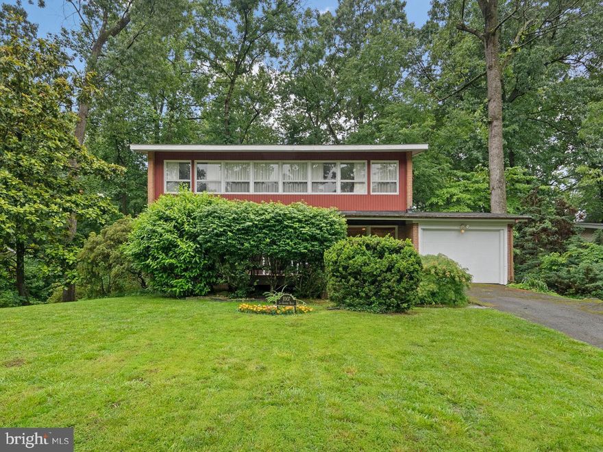 Spacious Mid-Century Contemporary Colonial with Private Outdoor Oasis! Welcome to this unique home, perfectly nestled on a fully fenced rear lot with a serene backdrop of mature trees and thoughtful landscaping. Ideal for both entertaining and everyday living, the home boasts an oversized rear deck and off-street parking, along with an attached one-car garage for added convenience.  Step inside to a classic center hall foyer with coat closet and powder room.  A private first-floor office with custom built-ins offers the perfect work-from-home setup.  The fully equipped kitchen provides direct access to the garage, while the sun drenched dining and family rooms impress with floor-to-ceiling windows and a wood burning fireplace with elegant brick and mirrored surround.  Ascend the striking floating wood staircase to the upper level, where you'll find a total of 4 spacious bedrooms--3 of which offer panoramic views of the private rear yard. 
 One of those 3 bedrooms includes a large walk-in closet and the hall full bath serves guests and family alike.  The generous primary suite features an ensuite bath, walk-in closet, and a dedicated dressing area.  The lower level offers even more space to unwind or entertain, with a second set of floating stairs leading to a versatile recreation room.  Highlights include a kitchenette, a second wood-burning fireplace, full height windows, a sliding door to the rear yard and a built-in bar with generous seating and shelving/storage for bottles and glassware.  A powder room, laundry/utility room, and walk-up exit complete this level. As an added advantage, the home features a whole house 20KW natural gas generator in case of power outages. This home is wonderfully located within minutes of the elementary and middle schools, the neighborhood swimming pool, and  just across New Hampshire Ave to the FDA campus. It is also a commuter's delight with a Ride-On bus service to the Silver Spring Metro just three doors down  and is an approx. 30-minute drive to downtown Washington, D.C. or Northern Virginia, and less than a 20-minute drive to Bethesda, College Park, Columbia, and Rockville.