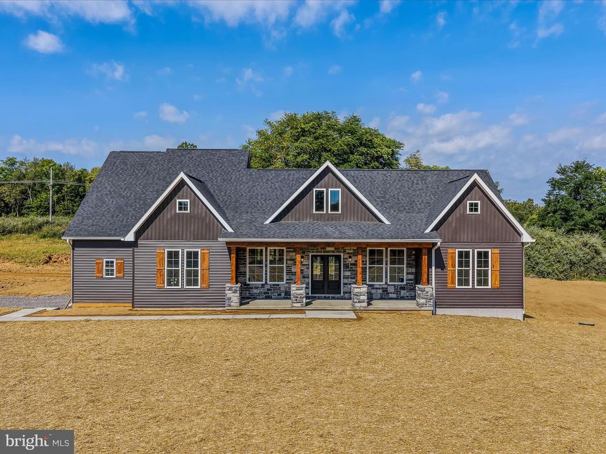 Discover refined country living in this stunning ranch-style home set on a peaceful 1.57-acre lot. With 5 spacious bedrooms, including a private upstairs suite, and 3.5 beautifully appointed bathrooms, this home offers the perfect blend of luxury, functionality, and privacy. Primary suite with elegant chandelier and crown molding create a serene, upscale retreat. Spa-like bath with freestanding soaking tub against a dramatic stone backdrop, walk-in tile shower, dual granite vanities with attached linen closet and an expansive walk-in closet. Chef’s kitchen boasting granite countertops and large island with pendant lighting, built-in microwave and wall oven, electric stove with stylish range hood, tile backsplash and abundant cabinetry. Living room with cozy gas fireplace with stone surround and wood mantel with an open-concept layout perfect for entertaining. Four bedrooms on the main level with ample closet space with the fifth bedroom upstairs with full en suite—ideal for guest or multi-generational living. An unfinished basement ready for future expansion. The exterior features include 1.57 acres of gently rolling land, a covered front porch and rear deck for outdoor relaxation with room to add a garden or outdoor kitchen. A paved driveway for smooth entry into the side load garage. Situated in a quiet, desirable neighborhood in Kearneysville, WV, with easy access to commuter routes, shopping, and schools. Enjoy the tranquility of country living without sacrificing convenience.