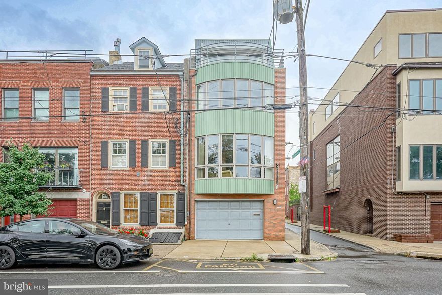 Welcome to 732 S Front Street- The Crown Jewel of "Little" Monroe Street and the head house of one of the best streets in Queen Village. This incredible 4-story custom-built home consists of 3 Bedrooms (plus large den) and 2.5 Bathrooms. Built in the 1960s, this home was designed to incorporate it's proximity to the river with its ship-like features, including porthole windows, bay windows and sliding doors, windows with stained/leaded glass, ship-like decks and railings, and light-filled rooms.The first floor consists of the oversized garage with interior access, the utility closet, a large powder room, the 4-Stop Elevator, and a den/ flex room with access to the private patio and rear parking pad. With over 3200 square feet livable space, this home has tons of light from three sides, sprawling bay windows on three floors, skylights in the primary sitting room and bathroom, two private balconies and a brick enclosed patio. The Patio and the primary bedroom windows also have powered and shuttered security gates to block any light and noise. 
Making your way to the second floor, you will find the Chef's Eat-In Kitchen with Sub Zero refrigerator and Jenn-Air Electric Range and rolling bay window with city views. From here you can pass through the large open Dining Area with Marble-Clad Gas Fireplace to the sunken Living Room with vast views of the Delaware River and small parklet across the street. Follow the stairs (or take the elevator) to the third level consisting of two bedrooms, a Hallway Bathroom, Laundry Room with the second HVAC zone, a Cedar Closet, and your very own Cedar-Covered Sauna! 
The final level is all yours, with a large sitting room with tons of closet space, an East-facing bedroom with wall-to-wall sliding glass doors leading to a Private Deck (another powered security gate which blocks out light and sound) , and a large Primary Bathroom with a Double Vanity,  Oversized Shower, Jacuzzi Tub, and a water closet with bidet and small rear balcony with City Views.
Come see what true original beauty this home holds within its walls.