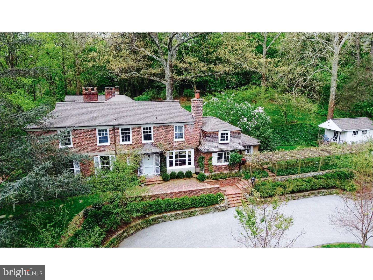 Classic Walter Durham colonial on 4 acres in Gladwyne, just down the street from Gladwyne village, and a short 10 mile drive to center city or 2.5 miles to the train. The moment you enter the driveway you will be taken with the curb appeal of this home and it's charming outbuildings, brick walls, walkways and grapevine covered arbor. This house has been respectfully expanded, renovated and maintained, and is well suited for today's living. The expansive windows let sunshine in and highlight views of the gardens, lawns and woods. Pass through the wisteria covered front entrance and you will begin to appreciate the thoughtful detailing of Walter Durham: random width heart pine floors, reclaimed bricks from old Philadelphia, and beautiful millwork. Arched openings flank the center hall leading to an inviting dining room on one side and the gracious living room on the other. The living room features a tall ceiling, oversized windows, a large walk-in fireplace and a terrace door. The modern kitchen has a tray ceiling, custom cabinetry, island with breakfast bar, stone counters and high-end appliances. The laundry room with a farm sink is conveniently located next to the kitchen. Casual dining in the breakfast room is enhanced by the scenic views of the arbor. Up a few steps from the front hall is the heart pine paneled library with fireplace and door to multiple terraces. Completing the main level are the family room, two wet bars, powder room and large screened in porch with an oversized wood burning fireplace - making it usable in three seasons. On the second floor, the home features a large master suite with a bedroom, dressing room, and bathroom with two separate vanities, Jacuzzi tub, stall shower and water closet. There are 4 secondary bedrooms, one with an ensuite bathroom, two bedrooms are connected by a jack and jill bathroom and the fifth bedroom/study has a half bath. Last but not least is the second floor great room, adjacent to the master suite and boasting a vaulted ceiling and birds-eye views. Additionally there are 3 outbuildings: a 2-car garage, a garden shed and a heated studio.