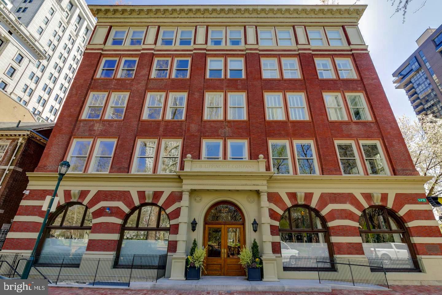 Before we entice you with the wonders of this beautiful residence, it’s important to note that the Lippincott is one of the few original buildings of distinction that line Washington Square. At one point in time, it was the largest publishing house in the world. And Washington Square has been, & still is, one of the most coveted locations in Philadelphia. Now for your tour:  Enter the  Residences  of the Lippincott through a tasteful newly upgraded lobby, hosted by a 24-hour concierge/door person(s).  Take the private elevator & arrive directly into the foyer of your home. As you enter the residence, there are a few things you will immediately take note of, they include: the gorgeous wood flooring that runs throughout, the neutral & soothing paint tones & the glorious, bright, open & airy floor plan. If you enjoy natural sunlight, you will love this property! Stroll to your right down a short hallway which opens-up to a kitchen, dining room & living room combination. The kitchen boasts endless quartz countertop space, including a large eat-on section with barstool seating. There are stainless steel appliances including a commercial grade Wolf oven & a Subzero refrigerator, & a tasteful tile backsplash. This kitchen is designed for the most discerning of chefs! The dining room is large & can accommodate multiple guests at your holiday get togethers. The living room is nothing less than magnificent, in part because its original exposed brick walls give it charm and character. It is also home to your gas fireplace which sets the stage for both entertaining and relaxation. From the living room there’s a door that leads you to your full-length back porch with wonderful Eastern views including treetops & your morning sunrises. This is the perfect place to sip your morning coffee & enjoy your evening glass of wine. Just off the living room there is a bonus room which can be used as a library, billiard room, or an expansive office. Until recently it was used as a music room and was home to a grand piano. Like the living room, it also boasts the charm of floor to ceiling brick walls & has a separate door leading out to the porch. As you may have noticed as you walked through all the aforementioned rooms & as you continue on with your tour, every room in the house has high and tray ceilings with tasteful definitions. This home provides you with three bedrooms and three full bathrooms. One of the bedrooms has an en-suite. The master bedroom is nothing less than grand. It has two walk-in closets (plus a wall of additional closet space) & a gorgeous master bathroom with two vanities separated by a large jetted soaking tub & a wonderfully tiled private shower. This property continues on to a wide spiral staircase that takes you up to a foyer with multiple skylights & two sets of sliders to your expansive rooftop deck. Here you will find a degree of privacy and the perfect place to either entertain or unwind. There are many honorable mentions to this property that will be experienced when you take your tour. The residences at the Lippincott just completed a full interior upgrade of the main lobby, floors & hallways & our unit unit has a New HVAC System that will be installed before you move in! There a comfortable & well-equipped gym & this unit comes with two ample-sized indoor parking spaces & an expansive storage room. The garage also boasts EV Charging Stations for both of your parking spaces. Lastly, this property’s location provides you w/unlimited inner-city conveniences. Walk out the front doors of the lobby & directly into one of the most gracious city parks in Philadelphia. Just a stroll in any direction will lead you to shopping venues, fantastic eateries, jogging & biking trails, dog parks, theaters, the arts, historic sites galore, area hospitals & immediate access to unlimited public transportation venues. Everything is literally at your fingertips! Do not hesitate. Schedule the personally guided tour today!