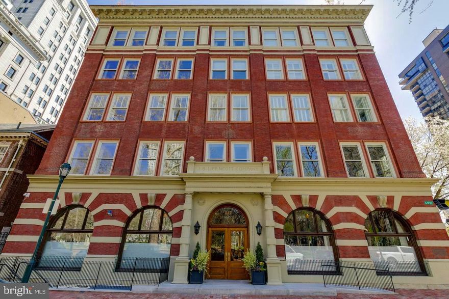 Before we entice you with the wonders of this beautiful residence, it’s important to note that the Lippincott is one of the few original buildings of distinction that line Washington Square. At one point in time, it was the largest publishing house in the world. And Washington Square has been, & still is, one of the most coveted locations in Philadelphia. Now for your tour:  Enter the  Residences  of the Lippincott through a tasteful newly upgraded lobby, hosted by a 24-hour concierge/door person(s).  Take the private elevator & arrive directly into the foyer of your home.  As you enter the residence, there are a few things you will immediately take note of, they include: the gorgeous wood flooring that runs throughout, the neutral & soothing paint tones & the glorious, bright, open & airy floor plan. If you enjoy natural sunlight, you will love this property! Stroll to your right down a short hallway which opens-up to a kitchen, dining room & living room combination. The kitchen boasts endless quartz countertop space, including a large eat-on section with barstool seating. There are stainless steel appliances including a commercial grade Wolf oven & a Subzero refrigerator, & a tasteful tile backsplash. This kitchen is designed for the most discerning of chefs! The dining room is large & can accommodate multiple guests at your holiday get togethers. The living room is nothing less than magnificent, in part because its original exposed brick walls give it charm and character. It is also home to your gas fireplace which sets the stage for both entertaining and relaxation.  From the living room there’s a door that leads you to your full-length back porch with wonderful Eastern views including treetops & your morning sunrises. This is the perfect place to sip your morning coffee & enjoy your evening glass of wine. Just off the living room there is a bonus room which can be used as a library, billiard room, or an expansive office. Until recently it was used as a music room and was home to a grand piano. Like the living room, it also boasts the charm of floor to ceiling brick walls & has a separate door leading out to the porch.  As you may have noticed as you walked through all the aforementioned rooms & as you continue on with your tour, every room in the house has high and tray ceilings  with tasteful definitions. This home provides you with three bedrooms and three full bathrooms. One of the bedrooms has an en-suite. The master bedroom is nothing less than grand. It has two walk-in closets (plus a wall of additional closet space) & a gorgeous master bathroom with two vanities separated by a large jetted soaking tub & a wonderfully tiled private shower. This property continues on to a wide spiral staircase that takes you up to a foyer with multiple skylights & two sets of sliders to your expansive rooftop deck. Here you will find a degree of privacy and the perfect place to either entertain or unwind. There are many honorable mentions to this property that will be experienced when you take your tour. The residences at the Lippincott just completed a full interior upgrade of the main lobby, floors & hallways & our unit unit has a New HVAC System that will be installed before you move in! There a comfortable & well-equipped gym & this unit comes with two ample-sized indoor parking spaces & an expansive storage room. The garage also boasts EV Charging Stations for both of your parking spaces. Lastly, this property’s location provides you w/unlimited inner-city conveniences. Walk out the front doors of the lobby & directly into one of the most gracious city parks in Philadelphia. Just a stroll in any direction will lead you to shopping venues, fantastic eateries, jogging & biking trails, dog parks, theaters, the arts, historic sites galore, area hospitals & immediate access to unlimited public transportation venues. Everything is literally at your fingertips! Do not hesitate. Schedule the personally guided tour today!