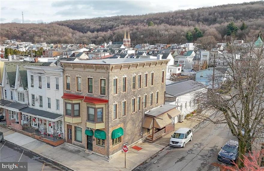 Multiple Offers Received. Highest and Best by 1/24 @ 5 PM. Unique and marvelous opportunity for an owner-occupied business with extra rental income or for the discerning investor! This brick corner property offers intricate detail in the brick work and a dramatic, attractive façade on both sides! The main level offers a commercial space, formerly a florist shop, connected to the main-level portion of a two-level residential unit. The residence offers front and side access, a side covered porch a lovely touch. The main level offers a spacious kitchen, full bath, and access to a rear, partially covered patio. A formal dining room with beamed vaulted ceilings peaking at 11’ connect to the front living room, also with 11’ ceilings, and a front foyer with gorgeous original tile. The upper floor offers a second full bath and five bedrooms! A separate entrance leads to the third floor offering two one bed/one bath apartments. Both offer an eat-in kitchen flowing nicely into a living room with bed and bath beyond. Each of the four unit are served by a separate electric service/meter. Situated on the town’s main street, visibility for the commercial unit is prime in the heart of downtown which also offers easy access to Route 81!