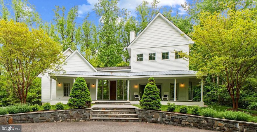 This exquisite five-bedroom, four-and-a-half-bath gracious estate home is ideally tucked away in the quiet and serene Annapolis community of Waters Ridge. Follow the private driveway to this one-of-a-kind modern farmhouse.  Architecturally stunning, and boasting a total of 5,415 total square feet, every element of the home is impeccably maintained and infused with the finest materials, fit, and finishes with high ceilings, architectural moldings, ebonized wood floors, and design-inspired details.  Refined principal rooms create a spectacular venue for entertaining, and transition seamlessly to cozy living spaces. The ultra-high-quality interior is functional, elegant and meticulously crafted, featuring a welcoming front foyer with a wall of windows, great room with wood-burning fireplace, french doors that lead to the porch, floor-to-ceiling windows and a hidden wet bar. The expansive gourmet kitchen features gleaming countertops, stainless steel appliances, custom walnut island with marble top and seating, and a dining nook with abundant windows.  The elegant formal dining room is highlighted by a wood-burning fireplace and doors leading to the blue stone back patio.  Follow the split staircase to an upper level that hosts two bedrooms and a full bathroom.  Take an additional private staircase to the spacious upper level primary suite, which has a serene ensuite bathroom with glass-enclosed shower, jetted soaking tub, and two custom walk-in closets.  Above the home’s two-car garage is a well-appointed guest suite with full bathroom, making for an ideal in-law or au pair suite. Continue to enjoy the home's amenities in the finished lower level where you can relax in the recreation area, or the den and bedroom, with adjoining design-inspired bathroom. There is also an expansive storage area. Further enhancing the appeal of this special property are the immaculately landscaped grounds, bluestone walkway that leads to courtyard with bluestone patio, large back deck, partial wrap around porch and a two-car garage. This home offers a private location where you can revel in the tranquility of nature on a private 2.17 acre lot, backing to the B&A trail, all while offering undeveloped water access on Cool Spring Creek and easy access to the shopping, restaurants, entertainment and commuter routes that Severna Park and Arnold have to offer.