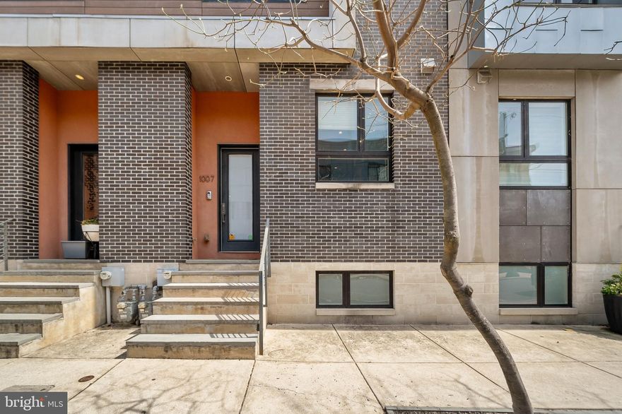 Welcome to 1007 S 17th Street, a modern and sophisticated home offering spacious city living with rare two-car garage parking, a private rooftop deck, and designer finishes throughout. Perfectly positioned in Graduate Hospital, this residence combines thoughtful architecture with everyday functionality across four beautifully finished levels.

Inside, you’re greeted by an open-concept main floor featuring a sleek chef’s kitchen with high-gloss cabinetry, quartz countertops, subway tile backsplash, and stainless steel appliances. Floor-to-ceiling windows and wide-plank flooring give the space a bright and airy feel. A striking steel-framed floating staircase leads into the expansive living room, where a full exposed brick accent wall brings texture and charm to the modern design. Thoughtfully crafted custom built-ins surround the media area, offering both style and storage. Oversized sliding glass doors flood the space with natural light and open to a generously sized private terrace—perfect for indoor-outdoor living and entertaining.

The fully finished basement offers incredible flexibility with a full bath, making it perfect for a home office, guest suite, gym, or media room. The second level includes two spacious bedrooms, a full bathroom, and a dedicated laundry room with tiled flooring, a utility sink, and a wet bar. The third-floor primary suite features a spa-like bathroom with a sleek double vanity and a glass-enclosed tiled shower, plus access to a wet bar just inside the door to your private rooftop deck with stunning skyline views.

Smart home lighting, dual-zone Nest thermostats, a new AC compressor, and fresh paint throughout complete the home. Located just blocks from Rittenhouse Square, Schuylkill River Park, and beloved neighborhood favorites like Ultimo Coffee, Sidecar Bar, Sabrina’s, Chicks, and L’Anima. You’re also just steps from daily essentials at Sprouts, Target, and Giant, making errands and grocery runs effortless. This home offers both luxury and convenience in one of Philly’s most sought-after neighborhoods.