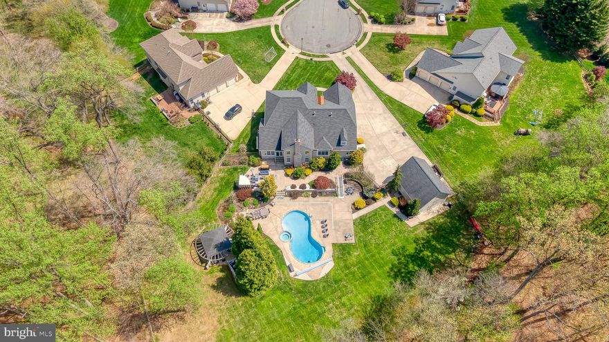 Stunning custom-built stacked stone colonial in sought-after Fox Chase offering three levels of exceptional living space. Designed for both everyday comfort and entertaining, this home features five fireplaces and expansive indoor and outdoor gathering areas. The kitchen is a true showpiece with granite countertops and high-end finishes. A luxurious main-level primary suite provides convenience and privacy, while an upper level primary suite and a full lower level separate in-law/nanny suite with private entrance offers incredible flexibility. Step outside to a resort-style setting with a huge pool, complemented by elegant paver stone patios, gazebo, pool shed and level yard. Car enthusiasts and hobbyists will appreciate the five garage spaces, including a detached two-car garage with office and half bath. A rare opportunity in an established Bel Air community.