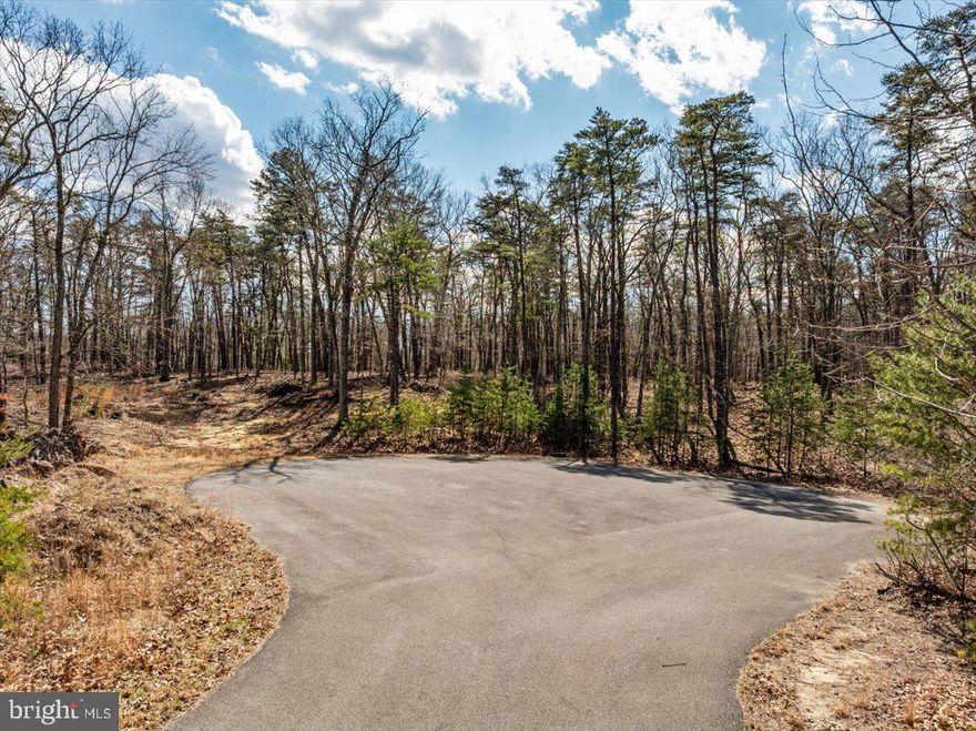 Tucked at the end of a quiet cul-de-sac, this 5.52 acre wooded lot offers the kind of setting many buyers hope to find but rarely do. The property sits slightly elevated above surrounding lots, creating a natural homesite with views and a peaceful sense of privacy. 
Mature trees provide a beautiful wooded backdrop without heavy underbrush, making it easy to walk and envision where your home could be built.  One standout feature is a large, established oak tree that would sit perfectly alongside a future homesite, if desired.  It would be a great natural focal point for the property and also add shade and character. 
With a gentle slope and multiple building locations, the lot offers flexibility for designing your home while taking advantage of the views and the surrounding landscape.  Paved roads lead all the way to the property, and there is no HOA! This means you can enjoy the freedome of a rural setting while still being part of an established neighborhood.
The location is within easy reach of some of the area's most popular outdoor destinations. Spend the day hiking, golfing, swimming, or relaxing at Cacapon Resort State Park, explore the shops and spas at Berkeley Springs, or enjoy the restaurants, shopping and historic charm of Winchester. 
For those commuting or seeking a weekend retreat from the city, the property is within a manageable drive of Northern virginia, making it a great option for a full-time residence or a peaceful getaway home.
The property covenants require a minimum home size of 1,600 square feet for a one-story home or 1,800 square feet for a two-story home (excluding porches, garages, and basements). A well and septic system will be needed. 
If you've been searching for land that combines privacy, natural beauty, and convenience to nearby towns and outdoor recreation, this property is well worth exploring!
Plat and full set of covenants and restrictions available.
