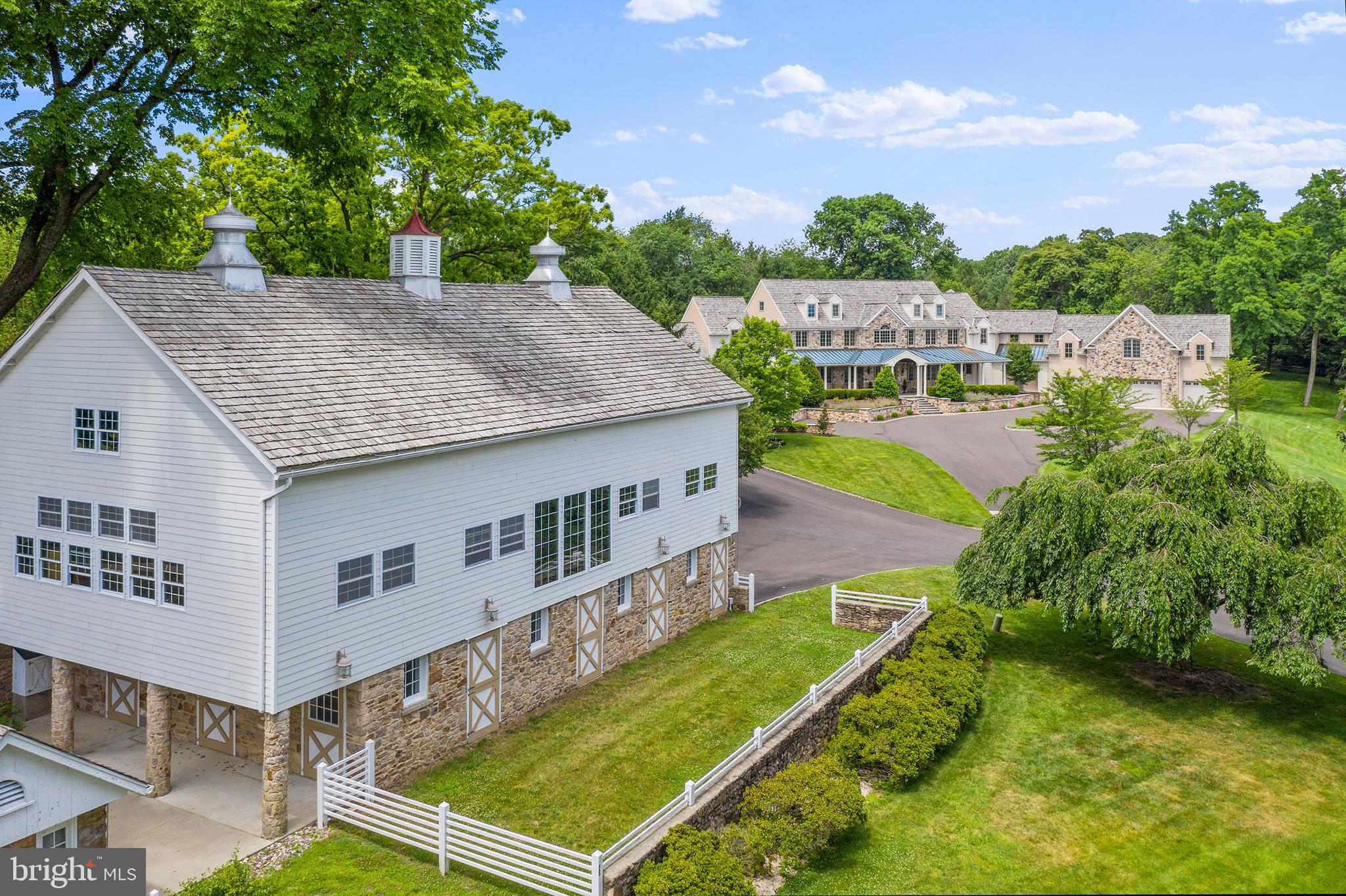 Looking for the perfect Compound for family, friends, guests in a placid & serene environment that checks all the boxes? Rarely comes along a property that provides the privacy & quality amenities offered in this exceptional Country Manor Home in beautiful Solebury Township, having all the trappings of a Bucks County Classic! As you enter the long tree lined drive you immediately experience a sense of peacefulness & calm. What lies ahead and once you reach your destination is singularly, a one of a kind place to call home in a tranquil parklike surrounding of sweeping lawn, mature trees, rolling pastures and a vista of treetops from this marvelous hilltop setting. The exterior of this remarkable home w/ its covered wraparound porch & Palladian Style window is a blend of attractive fieldstone, siding & stucco, which creates an "easy on the eye" balance of materials. Spacious but not intimidating, you are greeted by well-planned rooms, a hallmark of this approximately 11,000 square ft. residence. Onsite oak hardwood & exceptionally handsome wide plank dark walnut floors are featured throughout the house. Custom lighting & fixtures, the use of granite, stone, marble & quartz finishes add to the details & aesthetics. Clerestory, cathedral & vaulted ceilings throughout create a sense of airiness & elegance. Fresh new custom baths provide panache & comfort w/ eye catching details. A 19 X 22 foyer w/ its graceful curved staircase, wainscoting & travertine marble floor welcome you & set the tone for other comfortable rooms throughout. The great room w/ its lofty ceiling & mantled fireplace is flooded w/ light by its expansive windows. A wet bar & adjacent wine closet is conveniently located between the great room, dining room & kitchen. A banquet sized dining room w/ tray ceiling is perfect for large formal dinner parties. A wonderful chef's kitchen w/ large center island, lots of custom cabinetry & storage, sleek honed granite & quartz counters & decorative herringbone marble backsplash offers stainless Thermador 6 burner stove/oven w/griddle, 2 Kitchen Aid refrigerator-freezers, Microwave, 2 Bosh dishwashers, additional Thermador oven & a walk-in pantry. A large adjacent breakfast area w/wraparound window opens to the family room w/ cathedral ceiling, fieldstone fireplace & wall of French doors looking on the pool. Adjacent staircase takes you to the second floor. The sumptuous first floor master suite offers well placed windows, a fireplace, a truly luxurious marble bath w/ stunningly beautiful features, free standing soaking tub, oversized shower, plus 2 immense walk-in closets. Great private workspace is provided by a separate office off the foyer. The second floor offers 5 large bedrooms, each with full bath. A library w/ its striking curved wall provides outstanding space for reading & studies + an additional 30 X 31 flex space w/ French door overlooks an open field & completes this level. The walk out lower level provides great spaces w/ billiard room, additional daylight family room w/ fireplace, gym, full bath, + finished workspaces & potential for media room. A covered porch looks on to a fabulous in-ground saltwater, heated pool/spa w/ extensive blue stone patio & walkways. Prepare your favorite meals on the custom stainless Wolf grill, enjoy a cool drink & relax at the cabana wet bar equipped w/ ice maker & fridge. Celebrate life & share w/ family & friends in your own private oasis! The 3 bedroom, 3 bath guest house, once a former farm building & a charming creamery add character. A bank barn w/ 7 exceptional stalls & a groom's quarters is perfect for horses & pets; the upper level is marvelous w/ its clear span cantilevered cathedral ceiling allowing space for ground/garden equipment and outstanding storage. A tennis/sports court, extensive hardscape/ landscaping, generator & so many custom touches, make this property a true Winner by all Standards!
