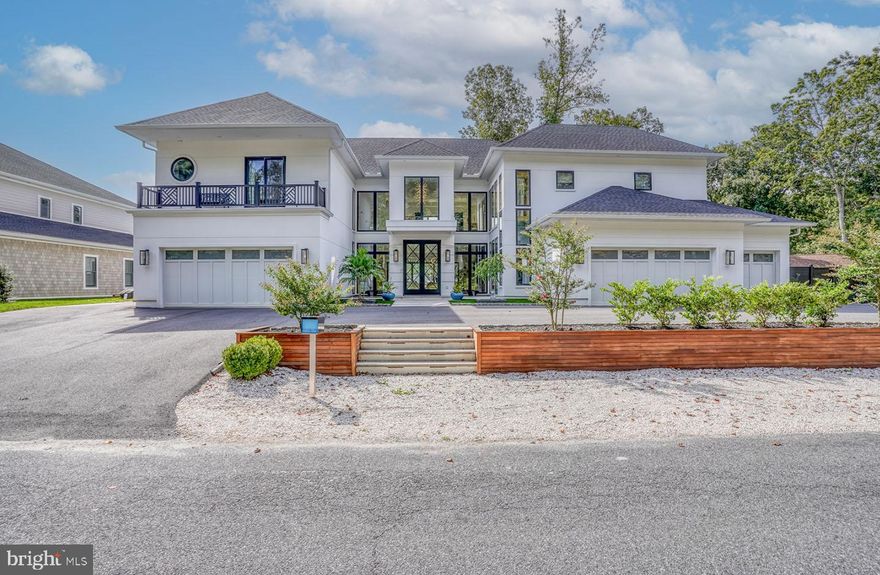 Location, location, location!  Welcome to this luxurious 5 car garage waterfront marvel at 104 W. Buckingham Dr., located in the coveted Rehoboth Beach Yacht and County Club. This sought-after Rehoboth Beach location is renowned for its beaches, diverse dining, minutes away from Tanger outlets and downtown shopping, and the entertainment night life that Dewey beach has to offer. This builder's personal home has modern sophistication with just over 7,000 square feet and is designed to take your breath away. Offering the ultimate amount of on and off-street parking, the craftsmanship shines in this vacation destination for people who dream big, love deeply, and live boldly. Set along Bald Eagle Lagoon, the house stands out among the rest boasting 2 deepwater slips for the Rehoboth Bay area. Offering one 20,000 lb boat lift, one wet boat slip, and two jet ski lifts it is truly a boater’s paradise.  The extra wide 6'x60' pier is decked with IPE decking for years of longevity.  Includes a 50 AMP power post with electric and fresh water on the dock.  The landscape lights and dock lights show off the exterior in style and function.  The spectacular fiberglass saltwater plunge pool is equipped with a waterfall and fire feature along with 3 outdoor showers, 2 of which are private and one down by the dock for a quick rinse after enjoying your day on the water.  The exterior decks on both floors have teak covered porches that allow you to have multiple areas to entertain and relax. An extra-large gas firepit on a paver gathering space delights guests for hours of waterfront conversation under the stars. With an open-air kitchen and a gas and EVO grill, your guests will enjoy fresco dining, laughter and unforgettable gatherings. Dazzling you upon arrival with its 2 exterior fire waterfall features and gas lighting it leads you to a spectacular mahogany front door.  Once inside you are greeted with 20'+ tall ceilings with a tiled foyer and exquisite lighting features and hardwood floors throughout the home. Step into the gourmet kitchen, where every detail is crafted for those who love to cook and entertain.  Adorned with quartz and Bertazzoni appliances and a walk-in pantry with additional prep space and second full size refrigerator this kitchen is the showpiece of this amazing house.  Views of the canal can be seen through the massive, fixed windows and double opening sliding doors in the back of the home.  A wood-burning limestone fireplace in one of the family rooms that overlook the bay makes for an extra cozy space on those cold nights. With a total of 4 living room areas, each equipped with large screen TVs allows owners and guests to each have a room to come home and unwind.  For the dog lover in mind, this house also incorporates a laundry room downstairs with dog grooming bathtub station. Enjoy the lighted open glass railing staircase or take solace in the bright double window shafted elevator to the top floor where the upstairs boasts 4 large bedrooms with their own private bath.  Add the functionality of a kitchenette and 2 laundry rooms upstairs, along with a living area that has the view of the lagoon from the wrap around rear porch with glass railings, the views are unparalleled. It’s a place which transcends the typical home and caters to your utmost comfort and desire.