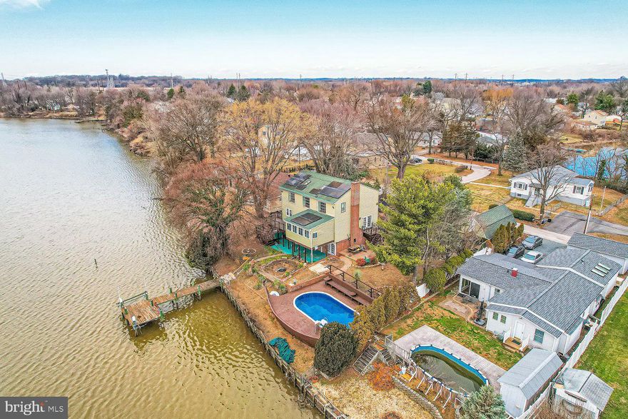 A water-lovers paradise, a 5BR/3BA expanded split foyer home located on a large lot with waterfront property in the quiet water oriented community of Chesaco Park!  Drive up past an oversized garage with two access doors and a fenced spacious front yard to the door into your forever home.  The beautiful wood staircase takes you up to the main living space beaming with an abundance of natural light, gleaming hardwood floors, and an open floor plan.  The spacious living room features a large bay window with a wide windowsill, ideal for house plants, and french doors to the side yard.  The amazing kitchen boasts tons of wood cabinets including two pantries, granite counters, a coffee bar, and a peninsula with seating. Through french doors, step into an oversized dining room with a built-in bench, a wall of windows that offer a stunning water view, and french doors to a large deck.  An oversized primary bedroom with two closets, a primary sized bedroom, and a full bath completes the main floor.  The stunning wood floors continue up the open stairs to the second floor and a large family room with vaulted ceilings, tons of natural light, skylights, built-in shelving, a gas fireplace and another spectacular view of the waterfront.  In addition, two sizable bedrooms, a full bath with a deep claw foot jetted tub, and three mini-split HVAC units completes this floor.  Onto the lower level offering an additional family room with a brick wood burning fireplace featuring a unique wood mantel, and the wild fifth bedroom with a private ensuite boasting a step-in jetted tub, and a walk-in shower.  French doors take you to a covered patio and the playground of your dreams.  Entertain on the upper deck, off the kitchen, then make your way to the yard with tiered landscaping, an above ground oval pool surrounded by a large wood deck that overlooks Back River, a walkway down to the dock offering space for a boat, and both a single and double wench systems.  This home is move-in ready and has so much to offer new homeowners, including a gas tankless water heater, new gas HVAC and recessed lighting! Enjoy this beautiful oasis!
