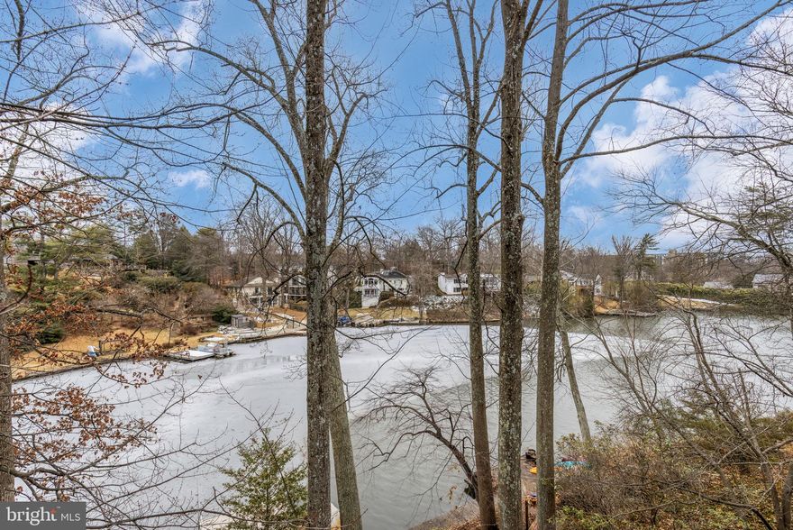 NEW PRICE! - LAKE BARCROFT | WATERFRONT - With over 150 feet of pristine shoreline and sweeping lake views from nearly every room, this 4 bed, 3 bath Mid-Century Modern home is a rare waterfront offering. Tucked among the trees on a quiet cul-de-sac and set on almost half an acre, it lives like a private retreat, perched above the water with a true treehouse feel.

A slate walk leads to double doors and into a light-filled foyer. Cathedral ceilings soar above the main living space, where a wall of glass frames the lake and brings the outdoors in. Hardwood floors, skylights, and clean contemporary lines highlight the home’s architectural character. The updated kitchen features  granite counters and a breakfast bar, and opens to the family room with fireplace with sliding doors leading to the upper deck, creating an easy, open flow for everyday living and entertaining. A main-level bedroom and full hall bath offer flexibility for guests or office space.

Downstairs, the spacious ensuite primary suite opens directly to the lower level deck and water views beyond, and includes a private sitting/dressing area and updated bath. This level also features the third bedroom, fourth bedroom/recreation room with fireplace, an updated hall bath, laundry, and a bonus room—ideal for hobbies, workouts, or extra storage.

Multiple decks invite you to unwind with morning coffee or sunset dinners overlooking the lake. Swim, fish, or paddle from your private dock, and enjoy landscaped grounds with mature trees and seasonal blooms. A semi-circular driveway and attached two-car garage add everyday ease.

Waterfront living, timeless mid-century design, and an unmistakable sense of calm—this is Lake Barcroft at its best.