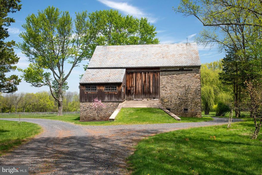 Set on an enchanting 98.68 acres, down a quarter mile drive through mature woodland, and nicely removed from a quiet country road in historic Bucks County, River Ridge Farm is a treasure. An historic red brick, one room school house is on the property, at entrance to the lane. Once known as the Guggenheim Estate, now beautifully transformed and embellished, this gentleman's farm is a quintessential representation of all that is unique to Pennsylvania architecture, in an exquisite and secluded setting, overlooking the Delaware River from high atop Chestnut Ridge Road. The circa 1823 pointed stone home was restored, with panache, in 2018. Only the best materials were used, including Azek trim, Hardi Plank siding, a 2018 slate roof with snowguards, and copper gutters and downspouts. A covered front porch beckons with bluestone flooring and a mahogany ceiling. Inside, wide plank floors span both levels of the home, enhancing the history and warmth. The large living room has two exposed stone walls, new, true-divided light Pella windows with deep window sills, and a wood-burning fireplace perfect for chilly evenings. Nearby, the den can serve as a first-floor bedroom, with its own gas-log fireplace. The floorplan flows naturally into the oversized kitchen boasting every modern convenience and top-of-the-line accoutrements.  Leathered granite countertops, with marble and grain bin backsplashes, merge seamlessly with abundant white cabinetry, a paneled Sub Zero refrigerator with separate freezer drawers, and a stainless steel Viking cooktop.  Adjacent, the original summer kitchen is now a dining room, featuring a cozy Jotul stove and opening to the wrap-around bluestone patio. Embellishing the patio is a timber frame pergola with led lights and a built-in Wolf grill with stone surround, and gas lamp lights that spring to light with the flick of a switch. The open and airy master suite will soothe and pamper. The bedroom keeps things simple and inviting, with 9' ceilings and plenty of windows. A private hallway opens to a walk-in closet with built-in organizers, while the master bath features marble countertops and a glass-walled, marble shower with rainfall showerhead. Rounding out the suite is a cozy room, suitable for an office or additional bedroom, with a fireplace, a hidden laundry closet and an additional sink. Two more bedrooms with large closets, and a hall bath complete the second floor, while a full attic offers room to expand. Downstairs, the lower level is heated, cooled and partially finished with a large exercise room and outside entrance to the bluestone patio and nearby garage. Multipurpose buildings are perfectly positioned amidst the acreage. A detached, heated, cooled and security-monitored garage has copper roofing, cypress ceilings, pine walls and easily accommodates 2-3 cars, with an attached ATV bay. The picture postcard, 1800s stone bank barn provides multiple purpose storage or a venue for conversion. For the horse enthusiast, the facilities include a large indoor riding arena, stable with 5 stalls, tack room and 2 run in stalls, an outdoor arena with grit footing and split rail pastures.  Miles of walking and riding trails lead one through the woods out to the tall cliffs overlooking the Delaware River. This intimate and rare setting in Upper Bucks County is a perfectly private oasis, yet still within easy driving distance to shopping, dining, and recreation. River Ridge Farm is an elegant estate from a bygone era, meticulously updated to embrace modern sophistication.