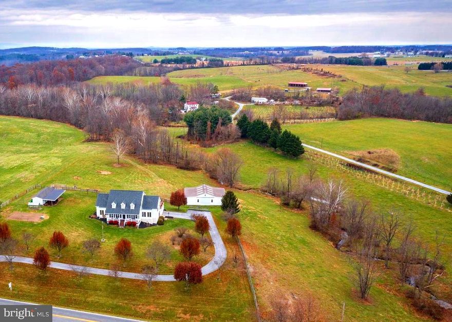 Turnkey perfection in the heart of the sought after and incredibly desirable Union Bridge community. TWO barns, paddocks and VIEWS for miles.  This desirable property is secluded from the hustle & bustle yet convenient to all major arteries. This farmette finds itself less than 45 minutes from the major metropolitan areas.   This impeccable estate is just under 10 acres featuring a gorgeous custom designed Creole Cape Cod of timeless quality construction -2 x6 exterior construction, 9 1/2' ceilings, 50 yr architectural shingles, solid oak hardwood floors as well as all new appliances in 2022.  The heart of the home features a spectacular gourmet light filled kitchen perfect for the in home chef or entertaining with ease on a larger scale.   In the kitchen, you'll enjoy picturesque granite countertops, rich designer cabinetry, a wall oven including a microwave/oven combo, electric induction stovetop with convection oven and a retractable downdraft fan.   A short walk through the dining room, family room with cozy fireplace and formal living rooms and you've reached the main level primary bedroom.     The relaxing primary bath is the embodiment of luxury with a programmable heated tile floor, stacked stone wall, luxe fireplace and clawfoot cast iron soaking tub. A walk in shower with dual shower heads, private water closet and Bluetooth speaker adds to the reserved level of ambience . The cathedral ceiling with skylight and spacious walk  in closet offers tremendous additional space. The cozy propane fireplace is the focal point of the family room that opens to a brand new outdoor deck space and continues onto the expansive low maintenance composite deck.  The walkout lower level features deep plush theatre seating and movie room, media closet and den/office.   In addition to brand new appliances, the new owners will appreciate a dual hot water heater system that provides consistent hot water to the entire household. The winding driveway is lined with fruit and flowering trees that add beauty to the mature landscaping around the home which is encased with perennial flower beds, mature shrubs and a grape arbor. 4 board oak and high tensile solar electric fencing and access to the meandering Isaiah Creek add perfect turnout for horses, cattle, llamas or the livestock of your choice.  2 barns, a chicken house with an enclosure are situated on several paddocks creating perfect rotation and turnout.  The sellers kindly share and offer their 2- custom constructed raised garden beds, a greenhouse, a large firepit, a 2 person sauna and a brand new children's playset to provide hours of activity and at home enjoyment.  This one of a kind custom estate home in the heart of Frederick County's tranquil countryside is a total luxury package with a list of must haves that simply will not last.