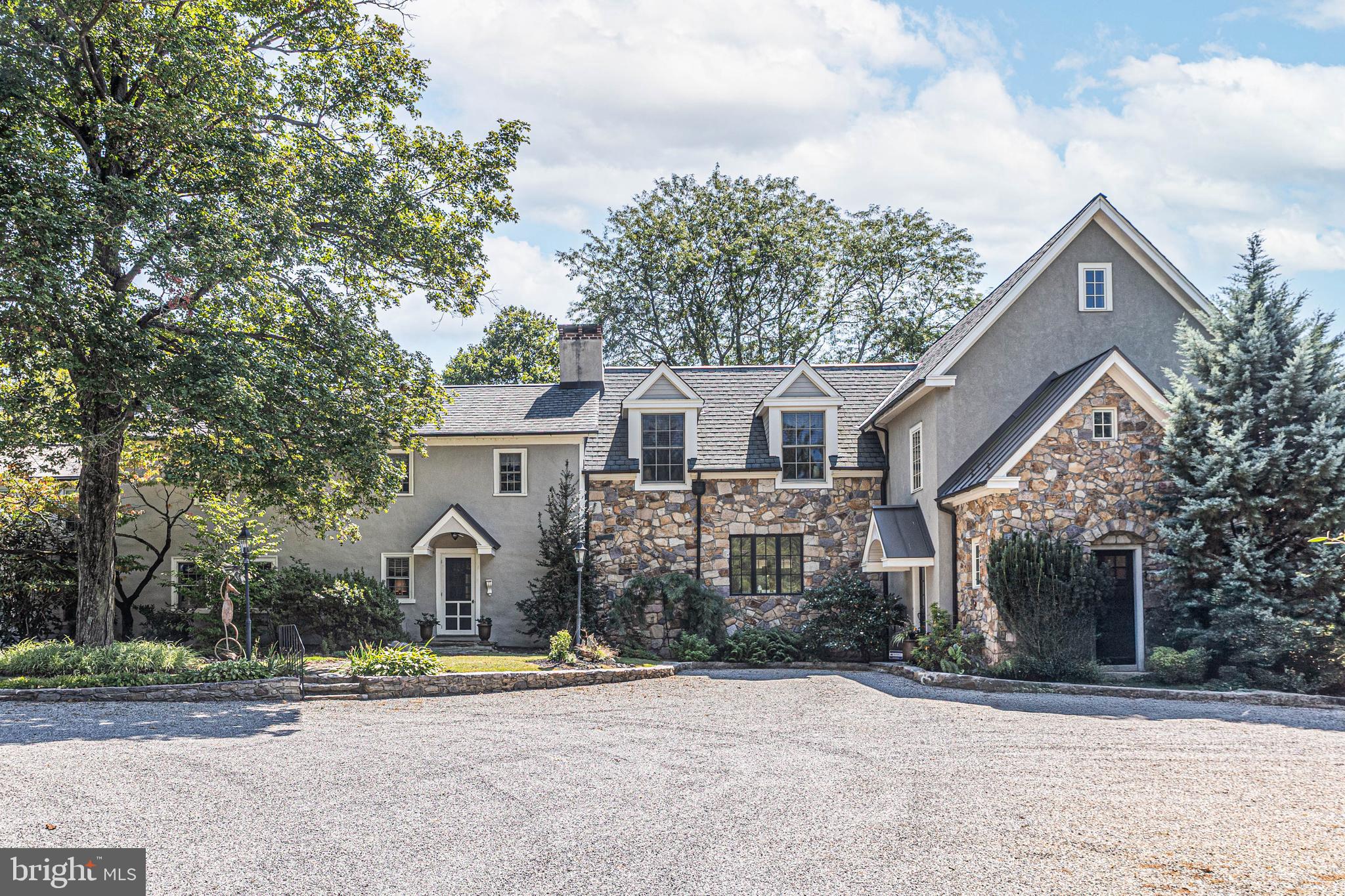 Tucked away at the end of a long, tree-lined drive, this circa-1800 stone colonial masterfully unites timeless historic charm with the sophistication of a thoughtfully designed modern addition. Set on more than three acres of rolling lawn and mature landscaping, the property is framed by stately trees, fieldstone walls, and pastoral views of neighboring farmland—one of Buckingham’s most picturesque settings. The original residence showcases timeless details: exposed beams, deep windowsills, wide-plank pine floors, and handcrafted millwork that speaks to its 19th-century roots. Complementing these authentic touches, a thoughtfully designed two-story addition enhances the home with lofty ceilings, expansive windows, and an elegant flow between rooms. The entry hall, in the newer wing of the home, features an elegant staircase and plenty of natural light which strikes the perfect balance of understated sophistication and antique charm. From here, the generous sized great room impresses with a soaring vaulted ceiling, stone fireplace, custom built-ins, and a wall of stonework—is an inviting space for family gatherings. Just beyond, the first-floor primary suite offers a private retreat with a sitting area, walk-in closet, and spa-inspired bath featuring a jetted tub, oversized shower, and custom cabinetry. French doors open to a flagstone terrace that invites seamless indoor-outdoor living. At the heart of the home, the chef’s kitchen is a showpiece with custom cherry cabinetry, granite countertops and a massive center island for casual dining. Culinary endeavors are elevated in this gourmet kitchen, appointed with Viking appliances, which includes a gas stove and grill, convection oven, bread warmer, an expansive refrigerator/freezer, and the added convenience of dual dishwashers. Directly off of the well-appointed kitchen is a wet/coffee bar which provides additional counter and storage space when hosting. A coffered ceiling with recessed lighting adds distinction, while French doors lead to a covered porch, perfect for outdoor entertaining. An adjacent sunroom with exposed stone walls and plenty of windows creates an additional gathering or dining area. Upstairs, two spacious bedrooms enjoy tall ceilings and arched windows, one with access to a balcony overlooking the property's bucolic grounds. A versatile bonus room and sun-filled full bath complete this level. An adjoining period bedroom, accented with exposed beams and a mantled fireplace, features its own updated bath, providing a comfortable guest or secondary suite. The residence also includes a self-contained living area with its own kitchen, bedroom, bath, and additional rooms above—an ideal arrangement for multi-generational living or private guest quarters. A charming stone smokehouse, barn, and scenic grounds add to the property’s unique appeal. With updated systems, zoned heating and cooling, and an exceptional location near New Hope, Doylestown, and easy routes to New York and Philadelphia, this remarkable estate is ready to be cherished by its next owners.