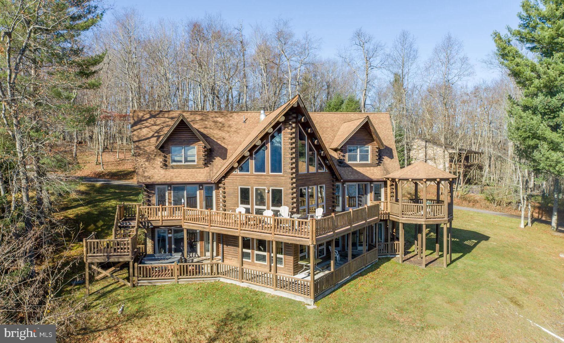 Stunning 6-Bedroom Kathadin Log Home with Breathtaking 180° views of Deep Creek Lake with Lake Access and a Boat Slip! This exceptional vacation home offers the perfect blend of rustic charm and modern luxury. Boasting 180-degree panoramic views of the sparkling lake, this property is a true mountain retreat. Every room is designed to capture the beauty of the surrounding landscape, with expansive windows allowing natural light to flood the interior and provide endless vistas of the tranquil water. With over 4,000 sq ft of living space, this spacious home features soaring ceilings, rich wood finishes, and an open-concept floor plan that’s perfect for entertaining. The main level living room, with its impressive stone fireplace, is the heart of the home, leading seamlessly into the kitchen and dining area. Whether you’re hosting gatherings or relaxing by the fire, this space offers comfort and style in equal measure. The home includes six generously-sized bedrooms, each offering a serene escape and 5 of them with picturesque lake views. Step outside to the expansive deck that spans the length of the home, perfect for enjoying morning sunrises . A boat slip provides direct access to Deep Creek Lake, offering the ultimate convenience for boating, fishing, and water sports enthusiasts. Additional highlights include a fully finished lower level with a family room, second fireplace, and walk-out access to the outdoor living spaces. The property is complemented by a detached garage. Whether you’re looking for a year-round residence, a vacation home, or rental home, this stunning log home offers unparalleled views, a prime location, and a serene lake lifestyle. High rental potential and projection. Don’t miss the opportunity to make this magnificent property your own!