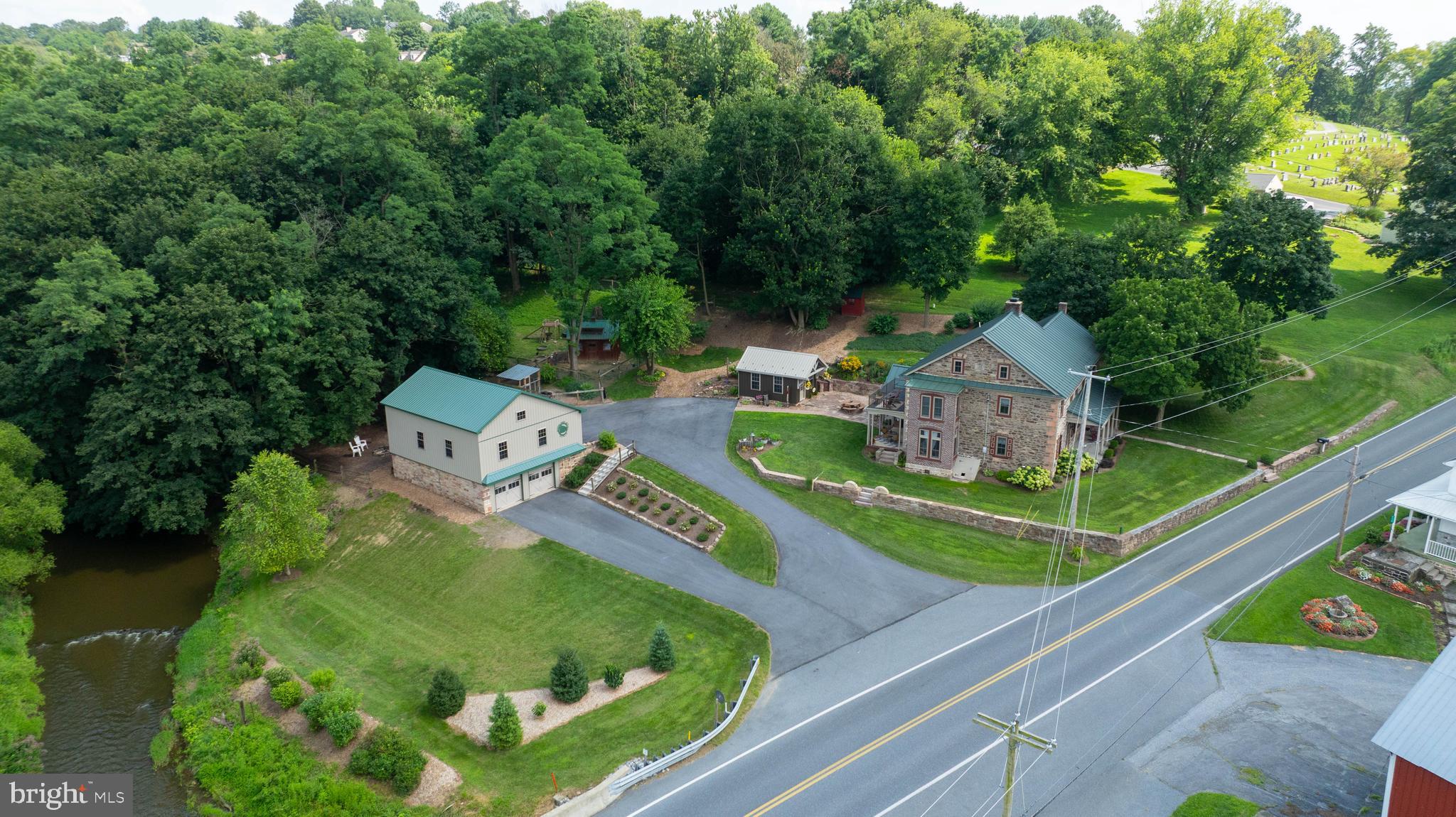 Beautifully renovated stone home dating back to circa 1771 w/1845 addition, nestled on 3.71 partially wooded acres overlooking Middle Creek. This is a rare opportunity to own a one-of-a-kind historic treasure blending charm, character & modern comfort. From the desirable 4-car detached garage/barn with workshop to the inviting outdoor living spaces, every feature of this property has been thoughtfully designed & impeccably maintained inside and out. Inside, you’ll find extensive millwork, deep window sills & the warm glow of wood floors, along with a showpiece custom white kitchen featuring granite counters, island w/breakfast bar, pendant/recessed lighting, exposed beam, brick accent wall, Samsung Bespoke glass door smart refrigerator & induction range w/air fryer—flowing openly into the spacious dining area by a stunning 2-sided stone fireplace that creates the perfect ambience for gatherings. Entertain in the family room highlighted by exposed beam and the stone fireplace w/cornerstone from the “Eagle Mill,” relax in the living room, enjoy a good book in the reading nook overlooking creek/fields, or sip coffee/dine in the private courtyard just off the kitchen. A charming mudroom with wash tub sink, built-ins, LVP flooring, wood accent wall, space for extra fridge/freezer & powder room with corrugated metal accents adds everyday convenience, plus an additional 2nd mudroom/office option with built-ins. Upstairs, the primary suite feels like a retreat w/spa-like bath including subway tile walk-in shower with glass door, soaking tub framed by stone accent wall, handmade wormy black walnut vanity with quartz top & copper sink, wood accents & high-end fixtures. Convenience of a 2nd floor laundry. Three additional spacious bedrooms (two are private), one with sunlit nook & balcony, provide a private escape. Outdoor living is unmatched—covered porches, sandstone stone patio, wooded campfire area by the creek & a recently finished magazine-worthy studio retreat w/cathedral ceiling, exposed beams, brick floor, granite counter & corrugated metal accents—the ultimate hangout space. Cool off in the creek or host gatherings w/lawn games near the firepit, and enjoy the outdoors with approximately 1/3 mile wooded trail ideal for walking, riding 4-wheeler, archery hunting & watching abundant wildlife/birds. Lush landscaping with perennials, ferns, hostas & herbs, plus thoughtfully set-up animal pens/barns. Just of a few of the recent updates (too many to list) include efficient replacement windows (2020), wall-mounted propane heat & hot water system (2017), and paved driveway (2022). Truly a once-in-a-lifetime property where history meets comfort, offering a lifestyle that is peaceful, private & unforgettable.