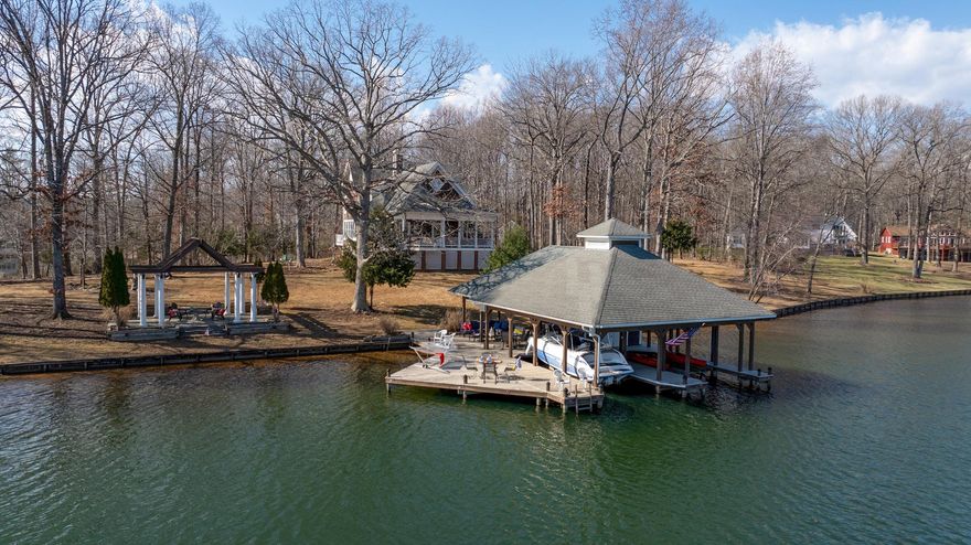 Where privacy, panoramic water views, and quality construction converge—this exceptional 5,790 sq. ft. waterfront residence delivers the ultimate Lake Anna lifestyle. Nestled on a premier peninsula lot on the Private Side of Lake Anna, this 1.5-acre property offers approximately 425 feet of pristine shoreline and breathtaking, wide-water views in every direction. From spectacular sunrises to tranquil evenings, the ever-changing lake backdrop becomes part of everyday living—visible from nearly every room.

A long paved driveway sets the tone, introducing a sense of serenity and seclusion as you arrive. Inside, the home is filled with natural light, blending Southern charm with timeless style. Thoughtfully designed for both entertaining and relaxation, the spacious layout features multiple gathering areas—ideal for hosting large groups or enjoying quiet moments.

The oversized kitchen, complete with a generous walk-in pantry, is designed to inspire—offering both function and space for effortless entertaining. Throughout the home, expansive windows frame stunning water views, creating a seamless connection between indoor and outdoor living.

The upper level features a spacious primary suite with multiple closets and a well-appointed bath, along with two additional bedrooms—each offering beautiful lake views. A standout feature is the expansive fourth bedroom, thoughtfully designed with a built-in raised sleeping platform and multiple adjoining sleeping areas—perfect for accommodating guests or creating a fun, flexible retreat.

The walkout lower level expands the home’s versatility, offering a comfortable den for media or gaming, a large flex room currently used as an office (designed as a bedroom), and a recreation space ideal for billiards or game nights. An unfinished nook provides the opportunity for a future kitchenette or bar.

For hobbyists and enthusiasts, the two-room workshop is a rare and valuable feature—complete with direct access to the attached two-car garage.

At the water’s edge, the boathouse becomes a gathering place for all ages. A true centerpiece of the waterfront experience, the covered boathouse is designed for both relaxation and entertaining. Featuring two boat slips with lifts, this impressive structure also offers a lakeside tiki bar, drop-down television for game days and movie nights, a spacious sun deck, and a dedicated storage room for all your water toys and gear. Whether hosting friends or enjoying a quiet sunset by the water, this thoughtfully designed retreat elevates lake living to another level.

A rare offering combining privacy, expansive waterfront, and versatile living spaces—this property is designed for making lasting memories at the lake.