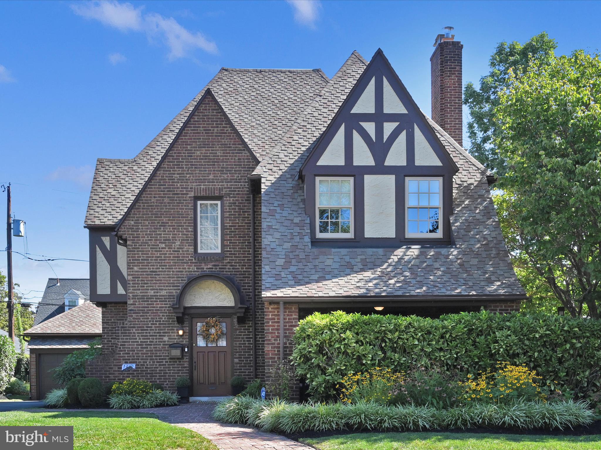 As you arrive at 465 Windermere Avenue, you’ll immediately sense the timeless charm of this captivating three-story English Tudor, perfectly positioned on a .22-acre “double” lot in the highly sought-after neighborhood of Drexel Park. The curb appeal is undeniable, showcasing a distinctive brick façade, steep gabled rooflines, and authentic half-timber accents that reflect the elegance of 1920's architecture. Thoughtful updates seamlessly complement its historic character, including a two-year young central air system, Andersen E-Series windows, a 50-year CertainTeed shingle roof, gleaming hardwood floors throughout, and a custom white kitchen- just a few examples of the many details that highlight the care and pride of ownership that define this remarkable home. A welcoming red door, framed by an arched overhang, sets the tone for this distinctive home. A second, more informal entrance invites you through a stunning arched brick entryway to a spacious covered patio complete with a ceiling fan and retractable privacy screen—an ideal spot for year-round gatherings or quiet evenings outdoors. This thoughtful outdoor space also provides a secondary entry into the living room through a door flanked by tasteful sidelights. Inside, the foyer greets you with warm hardwood floors, abundant natural light, and a preview of the grand formal living room. A turned staircase with crisp white trim and a polished wood banister highlights the craftsmanship that resonates throughout the home. The living room is anchored by a handsome brick fireplace with a traditional mantle, framed by oversized windows that flood the space with sunlight. Nearby, a cozy family room with built-in shelving flows seamlessly to the dining room, creating the perfect balance for both formal entertaining and casual living. The dining room makes a statement with its rich wallpaper, detailed millwork, and a dramatic arched window paired with a glass door to the outdoors. This space combines elegance with warmth, equally suited for holiday dinners or intimate gatherings. Just beyond lies a lovely outdoor patio (installed in 2011) overlooking the large, level yard—a serene backdrop for everyday enjoyment.The kitchen blends classic style with modern convenience: white cabinetry, leathered granite countertops, subway tile backsplash, slate flooring, and stainless steel appliances, all illuminated by plentiful windows. Two original Butler’s Pantries with 1920s hardware add charm & functionality, offering additional storage, counter space, and (6) pull-out cutting boards. A rear entry and mudroom enhance everyday practicality, while a secondary stairwell conveniently connects the kitchen to the main foyer staircase. Upstairs, a large picture window illuminates the landing. The primary bedroom (18x16) offers generous space, abundant natural light, a WIC, ceiling fan, and an en suite bath with subway tile and a tub/shower combination. Two additional bedrooms feature hardwood floors, roomy closets, and charming original glass doorknobs. A hall bath with subway tile and tub/shower serves this level. The 3rd floor provides a versatile 15x13 bedroom with two closets and a stylish ensuite bath featuring a claw-foot tub and black-and-white tile. The lower level offers ample storage, a laundry area with double sink, a convenient quarter bath, and multiple storage closets. A new insulated door provides egress to Bilco doors leading to the rear yard. What truly sets this home apart is the thoughtful investments the current owners have made, giving buyers peace of mind. Major improvements include: Central Air ('23), 21 Andersen E-Series windows ('23/'24) new driveway ('22), and two-car garage doors + opener('15). Additional updates include restoration and fresh paint of all half timbers & a CertainTeed 50-Year Shingle roof installed in 2010. Outside, mature landscaping, manicured gardens, and brick walkways frame this home in storybook charm. Make this your next chapter!