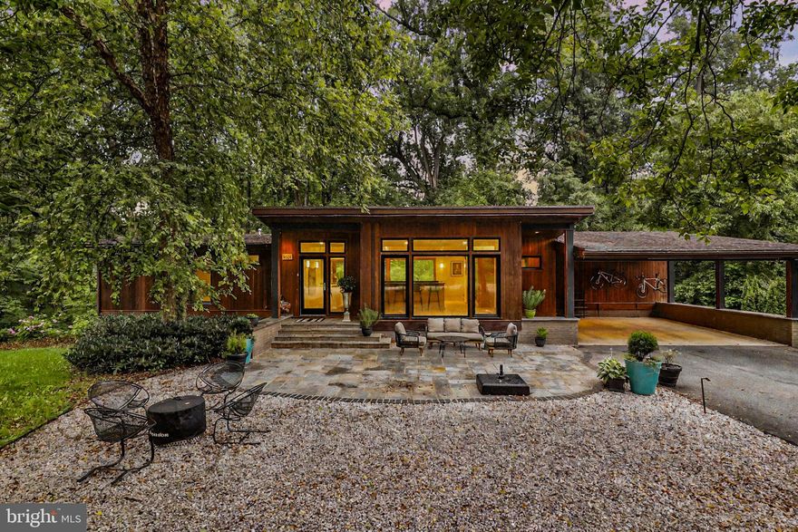 Welcome to 6921 Ayr Ln, a hidden gem tucked away at the top of a peaceful cul-de-sac in the heart of Bannockburn. This exclusive enclave of just 10 homes offers unmatched privacy and tranquility. Nestled beside a wooded lot, the property enjoys a lush, green backdrop—your own private sanctuary in an exceptional natural setting.

This contemporary retreat is a seamless blend of timeless design and modern luxury. With three spacious bedrooms, two and a half beautifully appointed bathrooms, and set on 0.42 acres, the home delivers effortless comfort and sophisticated style. Clean architectural lines, open-concept living spaces, and walls of glass flood the interior with natural light, creating a strong indoor-outdoor connection.

From the street, the home maintains a quiet, refined presence—defined by original wood siding, crisp geometry, and a canopy of mature trees that echo its Mid-Century Modern roots. Step inside, and the atmosphere transforms. Sunlight pours through expansive windows, and the interior opens into a bright, serene escape that invites relaxation and inspires connection.

Whether you’re enjoying peaceful solitude or entertaining with ease, 6921 Ayr Ln is a rare opportunity for modern living in an unparalleled setting.

The main entry level opens into a welcoming flex space directly off the carport. At the center of the home is the open-concept kitchen—featuring custom cabinetry and premium Wolf and Sub-Zero appliances—that flows seamlessly into the adjacent dining and living areas. Laundry and pantry areas are located directly behind the kitchen, making them both convenient and user-friendly. The sun-drenched living room—with its gas fireplace and built-in bookshelves—adds warmth and personality. Designed for everyday living and casual gatherings alike, this space brings people together with ease and comfort.

Two generously sized bedrooms, a stylish powder room, and a full bathroom with dual vanity complete this level—perfect for guests, family, or flexible use.

The garden level, bathed in natural light and with direct access to the backyard, expands the home’s livable space in a thoughtful, functional way. At its heart is a spacious family room with oversized picture windows and a wood-burning fireplace with gas hookup—perfect for cozy evenings, lazy weekend mornings, or casual entertaining. This level also features a private en suite bedroom, complete with wood-paneled ceilings, a built-in desk, a dressing nook, and a sleek bath with an oversized walk-in shower. A wet bar, custom built-ins, and two large storage rooms round out this versatile floor.

Outside, the magic continues. Step into a vibrant community with two neighborhood pool clubs, one just minutes away via a charming wooded path at the end of the cul-de-sac. Located in the highly sought-after Walt Whitman school district and close to walking and hiking trails, this home is just a short drive to Downtown Bethesda, Potomac Village, Whole Foods, and Washington, D.C.

With beloved neighborhood traditions like Food Truck Fridays and an annual talent show, Bannockburn is more than a location—it’s a true community. And 6921 Ayr Ln is your chance to be part of it.