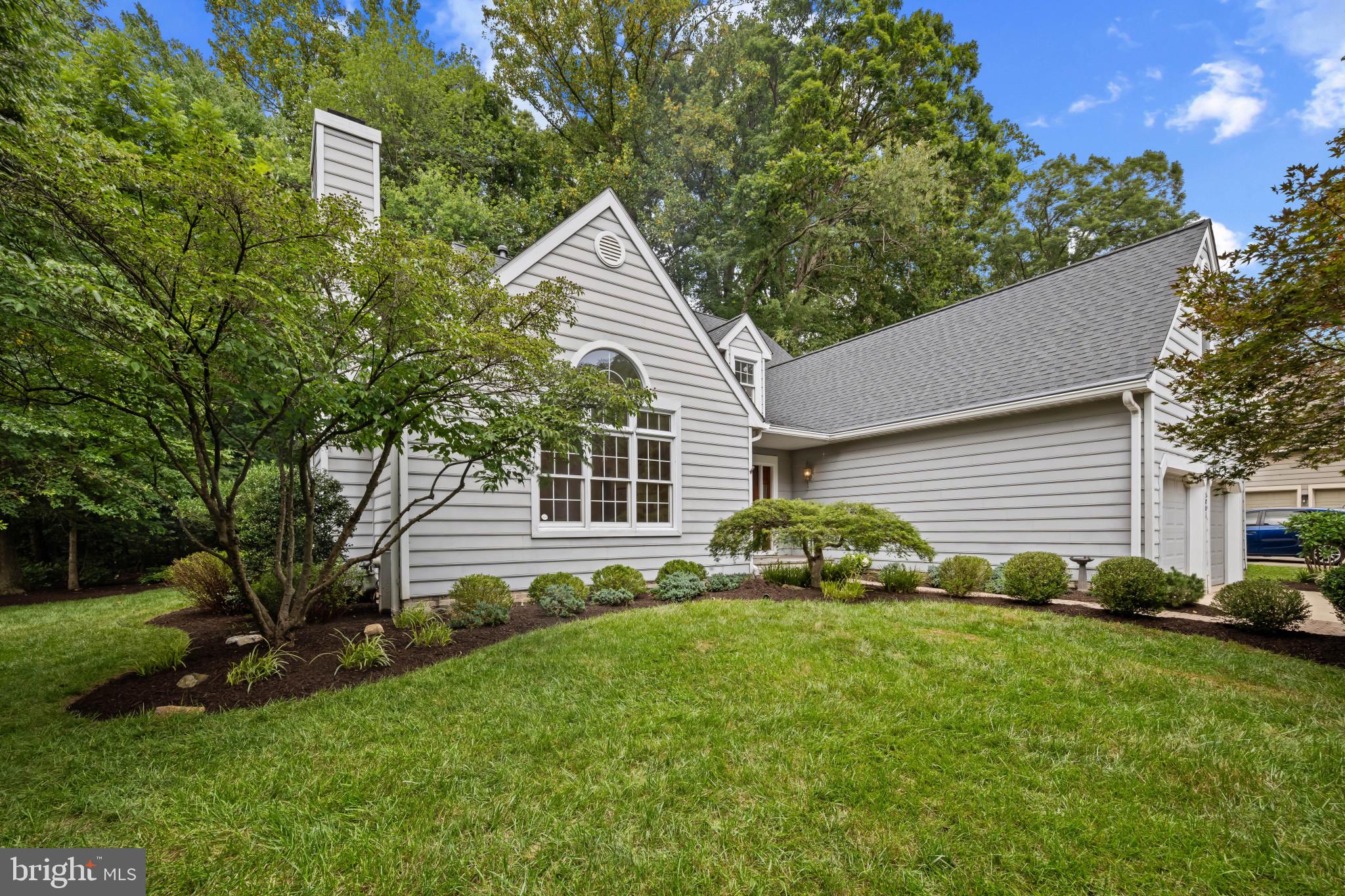 Welcome to this beautiful Colonial residence in sought-after Hobbits Glen, offering 2,446 square feet of refined living space with 4 bedrooms, 2 full baths, 2 half baths, and a 2-car carriage garage. Step into the impressive two-story foyer, where gleaming hardwood floors flow throughout the main level. To one side, a grand arched entry leads to a versatile office or lounge adorned with floor-to-ceiling built-in bookshelves and a charming window nook. On the other side, the light-filled living room boasts vaulted ceilings, custom built-ins offering abundant storage, and a cozy gas fireplace. A built-in workspace and optional dining area seamlessly bridge the living room and the expansive eat-in kitchen, with vaulted ceilings, a center island with seating, white cabinetry, double ovens, stainless steel appliances, and charming built-in shelving for cookbooks or décor create a perfect blend of style and function. A spacious pantry offers ample storage, while sliding glass doors invite you to step out to the backyard. The main-level owner’s suite offers an abundance of natural light, lush new carpeting, and a luxurious en suite bath with a double vanity, soaking tub, glass walk-in shower, and a custom closet system—just steps from the main-level laundry for ultimate convenience. Upstairs, you’ll find three generous bedrooms filled with natural light, a hall bath with tile and a shower/tub combo, and a large walk-in storage closet. The finished lower level features a large carpeted recreation room with recessed lighting, a half bath, and a substantial unfinished storage area. Outdoors, enjoy a serene stone patio with a pergola and beautifully landscaped gardens backing to lush greenery and a tranquil tree line—an ideal private oasis.