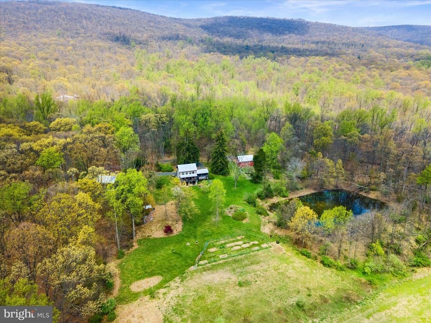 Here is your once in a lifetime opportunity to own this tastefully remodeled, historic 1850s log cabin on over 143 acres! Yes, you read that right! Not only do you personally own 143 acres, but bordering this property is over 3,400 acres of state game land! This home was once situated in Upper Bern township and was disassembled and moved to its present location around 2008-2009. The current owners decided to build green with this modern passive solar home. So many features were carefully and meticulously thought out and executed.  From the insulated concrete form walls for maximum insulation and strength to hold up the heavy structure, to the 100 year old hemlock floor joists, the large oak center beam or “summer beam” that was from an old barn, and the beaded pine wall board salvaged from the home before it was disassembled and transported to its present location. The goal was to restore this home with its original character while simultaneously bringing it up to the 21st century standards, and they did just that! And you cannot beat the location! Situated near I-78, but still offering an incredible amount of privacy, this is perfect for the person who wants to have their own getaway while still being close to major routes and cities. As you drive down the private gravel road you will find your paradise that boasts two large spring fed ponds great for fishing, a creek and several small streams tucked back in the woods, a storage barn with tons of potential, another 1880s barn that was turned into a detached two car garage/shop, and some truly incredible views. In the front yard are mature rhubarb and asparagus plants, apple trees and blueberry bushes. Before you enter the home you will notice the lovely porch with beautiful Pennsylvania blue stone and massive flagstones that came from a demolished mansion in Pottsville that are used to divert the storm water. Speaking of storm water, there are two 2000 gallon underground cisterns where the storm water collects from the gutters to be used for fire suppression if ever needed. Entering the home you will be immediately greeted with a lovely entryway with heavy, insulated doors and gorgeous old barn wood flooring. The kitchen is directly to your right with updated granite countertops, warm tones, plenty of counter space and a lovely window with a gorgeous view of the mountains and farmland. The open living/dining room has plenty of space and natural light with two exterior doors. One that leads to the front porch, and the other leading to the amazing side porch that is perfect for entertaining and relaxing on those breezy spring and summer nights. A convenient powder room is located off of the living room as well. Heading upstairs you will admire the gorgeous, solid staircase with wood that also came from an older barn. An office/pass through bedroom greets you as soon as you get upstairs. There is also a full bath and a guest bedroom to your right, and a sizable master bedroom to your left. Another great feature to note is that each bedroom has an attic fan to draw all of the heat out during the hotter months. Heading down to the basement you will notice the tall ceilings and copious amounts of light coming in from outside. This lovely walkout basement offers a nice red/brown concrete floor, a closed combustion fireplace in the living area, a reading nook or office on the opposite side and a full bathroom. The laundry area, storage, and a bonus wine/root cellar are also located in the basement.  In addition, to preserve all of its beauty, this property was recently placed in Berks Conservancy. Schedule your tour today and start planning your future homestead on this magnificent parcel. Please do not drive down the driveway without a confirmed appointment.