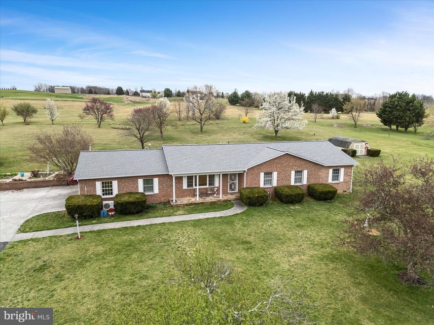 Discover your dream retreat with this charming all-brick rancher, perfectly situated on 7.47 acres of picturesque landscape, just minutes from town, shopping, and schools. This exceptional property includes an additional parcel with previously approved 1 bedroom perc, offering additional opportunity or buffer space.  Step inside to hardwood floors and an traditional layout that boasts a spacious primary suite with walk-in closets and a primary bath featuring a walk-in shower. Stainless steel appliances and corian countertops top the kitchen highlights, with an island and bar seating and ample cabinet space.   Additional generously sized bedrooms provide comfort and versatility for family and guests.
The massive den is perfect for cozy gatherings, while the sunroom, with gorgeous stone floors,  steals the show with stunning views of the landscaped acreage and courtyard garden.  There is even a small portion of the yard fenced, convenient for pets!
Outside, take advantage of the detached two-car garage, two powered sheds, an additional powered garage with two additional garage bays and workshop area, and a charming gazebo ideal for relaxing in the shade.  Whether you’re hosting gatherings or savoring quiet moments, this property offers endless possibilities. Don’t miss your chance to own this serene oasis—schedule your private tour today and experience country living just moments from modern convenience. Please Note: home has an HVAC system for heat and air.