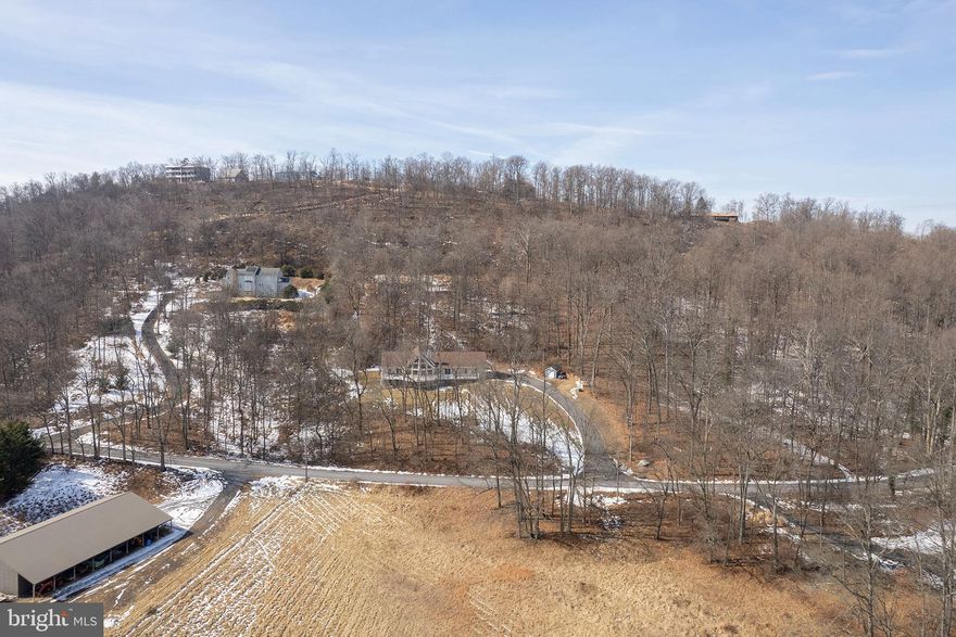 Stunning 4 Bed / 3.5 Bath Chalet on 3.26 Acres with Over 6,300 Sq Ft — Minutes from Winchester

This exceptional chalet-style home offers over 6,300 sq ft of living space on a private, partially wooded 3.26-acre lot just minutes from Winchester. Designed to capture mountain views, the home features soaring cathedral ceilings, a striking stone fireplace, and walls of windows that flood the great room with natural light. A second-story loft with a family room overlooks the main-level great room, adding to the home’s open, airy feel. Hardwood floors run throughout the main level, which opens to a spacious wrap-around deck—perfect for entertaining or simply enjoying the views. The primary suite is also on the main level and features a jetted tub and a walk-in closet. A main-level laundry room adds everyday convenience. The gourmet kitchen offers an island, breakfast bar, new dishwasher, and microwave, while the main-level den includes a built-in bench with extra storage. The finished walk-out basement is ideal for guests or multi-generational living, complete with a wet bar, kitchenette, second entrance, sink, and refrigerator. You’ll also find a spacious main-level workshop with shiplap walls and a large sink—perfect for hobbies or projects. Additional features include an oversized 2-car garage, Culligan water softener, pressure tank, sump pump with new grinder pump, Aqua PEX plumbing, solid oak doors on the main level, 2x6 exterior walls with extra insulation, and durable HardiePlank siding. The chimney has been regularly maintained.
Recent updates include: Roof (2024), Main-level HVAC (2025), Septic pumped (2025), Brine tank replaced (2025), Back deck (2022), Gazebo (2025), Microwave (2025), Whole house painted (2025), Fresh landscaping (2025), Shed (2025),  & Washer & dryer (2025). This is a rare opportunity to own a spacious, well-maintained mountain-view home with privacy, quality construction, and extensive updates—just a short drive from Winchester. Check out our 3-D Tour link attached to the listing!