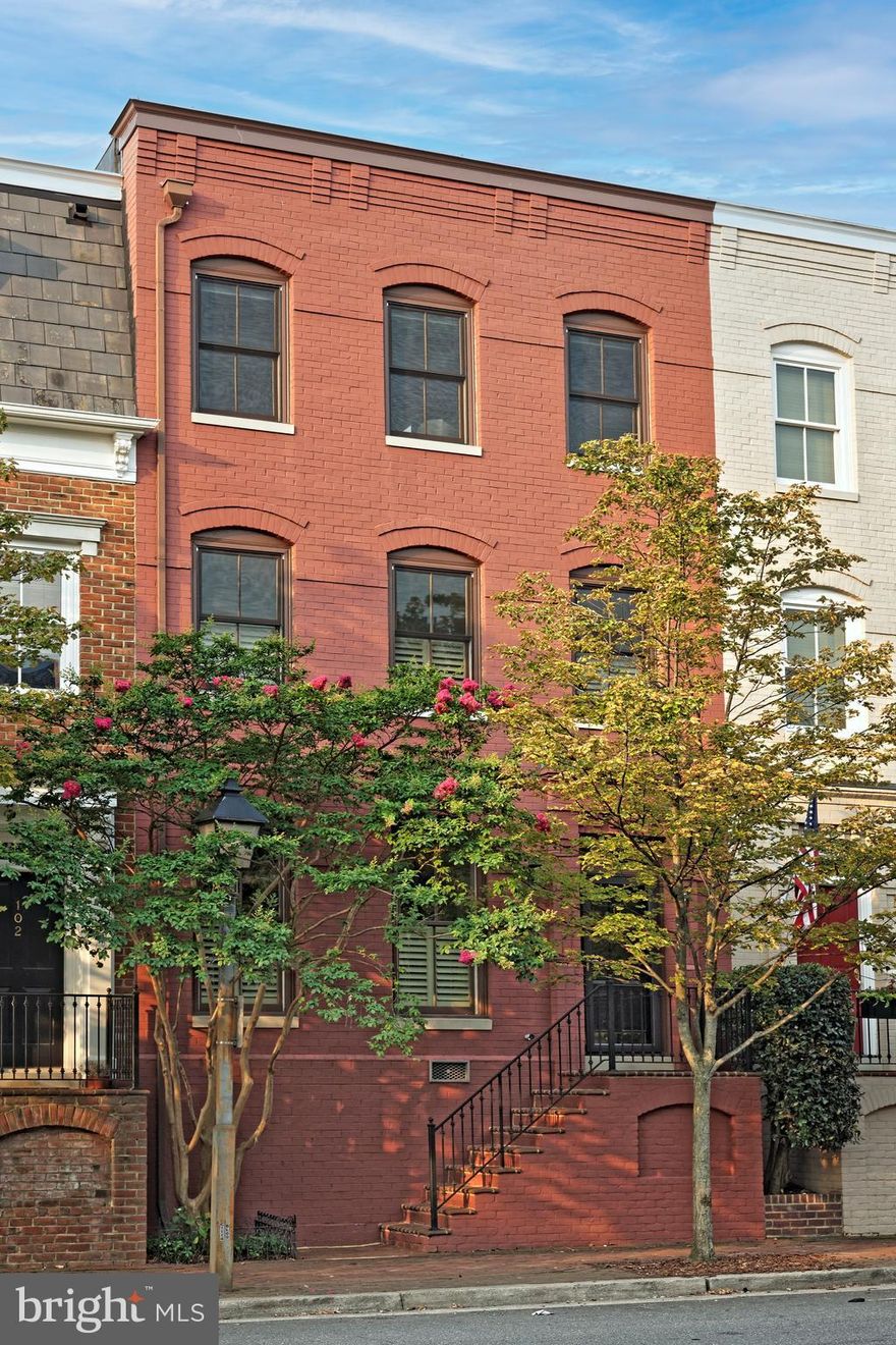A stunning, sophisticated Queens Row 3BR, 3.5BA townhouse offers delightful views of the Potomac River and Founders Park just out the front door.  A welcoming, long entrance hall with classic antique brass chandelier opens with a wide door casing to the impeccable living room featuring two tall windows with plantation shutters, high ceilings, deep detailed moldings, and a gas fireplace flanked by custom built-ins.  The spacious Manor Gray dining room includes a custom designed and made chandelier and is perfect for family gatherings.  A bright kitchen offers cove ceiling lighting, pendant lights, Casablanca ceiling fan and a custom pantry.  The wall of windows floods the space with natural light, highlighting the beautiful light wood floors into the adjoining family room with a Samsung TV.  French doors open to a private stone patio with raised brick planter filled with lilac bushes, azaleas and evergreens outlining this unique outdoor space.  A luxurious primary suite awash in natural light from three windows with plantation shutters, built-in speakers, his and her walk-in California Closets and a sizable marble bath offers a seamless glass shower, soaking tub, and double vanities.  The 2nd floor library has a gas fireplace with marble surround flanked by custom bookshelves and extensive moldings. Two generous en suite guest bedrooms on the 3rd floor feature hardwood floors, ceiling fans,  custom walk-in closets with built-ins, one currently being used as a home office.  The peaceful terrace with mature plantings also includes a natural gas line for a grill or fire pit, a storage shed, and the area is pre-wired for audio speakers.  Two assigned parking spaces located steps from the private terrace complete this fine residence.