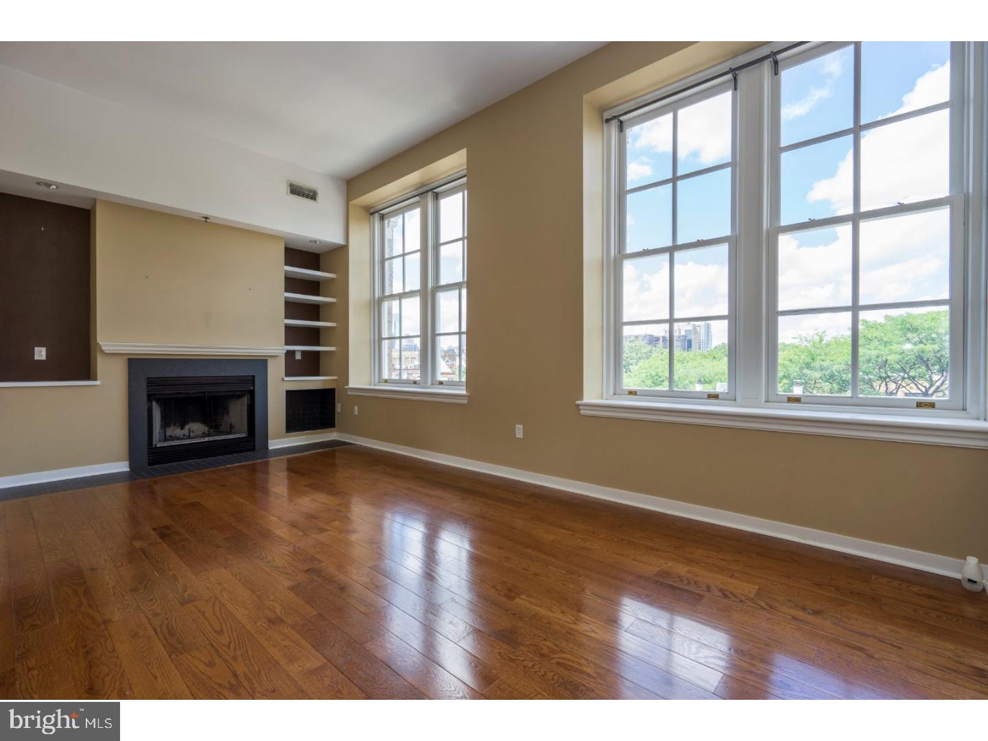 Rarely offered in the heart of Queen Village! Beautiful and bright 2 bedroom, 1 bath condo ideally located within the highly demanded Meredith School catchment. Enjoy fantastic tree top & Center City views from almost every room. Huge, energy-efficient double-pane windows & up to 12' high ceilings. Spacious and fully equipped kitchen with loads of cabinet & counter space. Open layout in the living/dining room area featuring a wood burning fireplace, custom built-ins & high hat lighting, spacious enough for a separate eating area. Hardwood floors throughout. Extra storage in the basement. Elevator. Pet friendly with a dog park only 1 block away. This quiet building used to be a school, and was converted into 14 units in the 80's. Easy access to Center City, South St, bars, restaurants and all major highways.