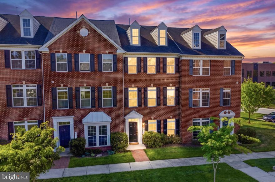Welcome to this beautifully maintained, expansive brick-front townhome, where abundant natural light and an elegant design create an inviting atmosphere from the moment you arrive. A truly rare find in townhome living, this property boasts effortless parking and storage with a two-car garage and an accompanying two-car driveway. The versatile entry level is thoughtfully designed to adapt to your lifestyle. It features a bright, flexible space perfect for a fourth bedroom, private home office, or media room, alongside an additional spacious room already roughed-in for a third full bathroom. A dedicated laundry and mudroom area with a convenient closet completes this highly functional ground floor, keeping everyday clutter out of sight. Upstairs, the main level showcases a breathtaking open-concept layout grounded by gleaming hardwood floors and illuminated by large transom windows. At the heart of the home is a gourmet kitchen outfitted with 42-inch cherry cabinetry, sleek granite countertops, a massive walk-in pantry, and updated stainless steel appliances (2021). This culinary space flows seamlessly into a sprawling family room and out to a beautiful composite deck, offering an ideal, low-maintenance setting for morning coffee or evening entertaining. A well-placed powder room perfectly serves this central gathering space. The hardwood flooring continues onto the upper level, which hosts three generously sized bedrooms and two full bathrooms. The true showstopper is the luxurious primary suite. This private sanctuary boasts a large walk-in closet and a spa-inspired en-suite bathroom complete with a dual-sink vanity, a deep soaking tub, and a custom-tiled shower. Elevating the suite further is a stunning private loft, featuring a beautifully designed wet bar and wine refrigerator, the ultimate retreat for a secluded home office, elegant sitting room, or cozy reading nook. Perfectly situated for ultimate convenience, this home offers unbeatable accessibility to the premier shopping and dining at Arundel Mills Mall, as well as major commuter hubs including the NSA, Fort Meade, and BWI Airport. Seamlessly blending executive comfort, sophisticated style, and an unmatched location, this move-in-ready gem is an exceptional opportunity you will not want to miss.