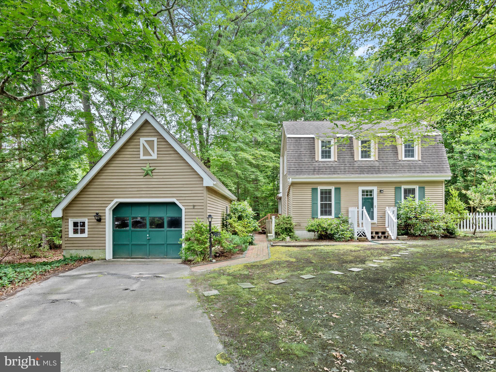 Tucked away on a peaceful cul-de-sac and surrounded by trees, 5 Lighthouse Court offers storybook charm in the heart of Ocean Pines.
This delightful home evokes the warmth of an English cottage, with a cozy living room featuring a brick gas fireplace framed by twin octagon casement windows. The space flows effortlessly into a sunny breakfast nook, also graced with an octagon window—and continues into the well-appointed kitchen, where granite countertops, stainless steel appliances, abundant workspace, and recessed lighting over the sink create an inviting cooking environment.
A step-down leads to the sunroom, a tranquil retreat with a full wall of casement windows that frame lush, green views. The first floor also includes a comfortable bedroom, a full bath, and a convenient laundry area.
Upstairs, two additional bedrooms feature built-in bookshelves tucked into the closets and share a full hall bath with a walk-in shower.
Step outside to enjoy the new composite deck just off the sunroom—an ideal spot for grilling and dining al fresco. The backyard offers room to create a cozy fire pit area, while a detached one-car garage is complemented by a charming courtyard space on the opposite side of the home.