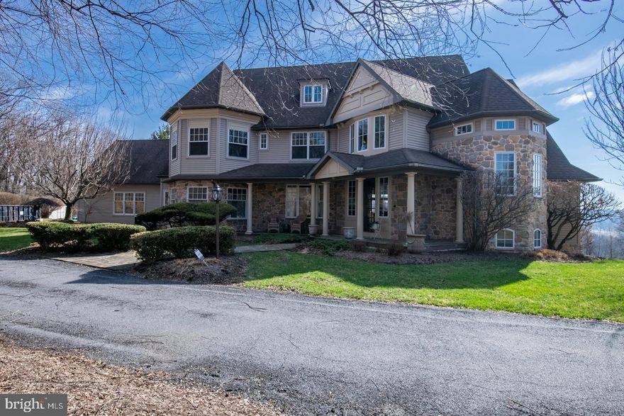 Privacy abounds on this exceptional estate set on 14.5 sprawling acres, offered for the first time ever. This luxurious two story stone and vinyl residence delivers over 6,700 square feet of refined living space, featuring 5 bedrooms, 5 full and 2 half baths, primary suites on both the first and second floors, and a heated in ground pool—an ideal blend of elegance, comfort, and seclusion.
Step inside from the covered front porch into a grand two story foyer that leads directly to the expansive family room, highlighted by a stone wood burning fireplace and French doors with transom windows that open to the rear patio. The space flows seamlessly into the chef’s kitchen, designed for both everyday living and entertaining.
The kitchen is beautifully appointed with granite countertops, a generous center island with seating, tiled flooring, a tumbled marble backsplash, and a full suite of premium appliances including a Sub Zero refrigerator, double wall oven, cooktop, warming drawer, and reverse osmosis system. A sun filled breakfast nook with second story overlook offers stunning views of the surrounding property and is perfect for informal gatherings.  Just off the kitchen, a dedicated coffee bar provides ample storage, while the butler’s pantry features extensive built ins and exceptional space. Adjacent to the family room, the wet bar is equipped with granite counters, tile flooring, a wine refrigerator, mini fridge, and ice machine—ideal for entertaining.
Formal living and dining rooms add classic sophistication. The dining room includes chair rail detailing, two storage closets, and a large picture window that fills the space with natural light, while the living room showcases detailed crown molding and a gas fireplace.
The main level also offers outstanding flexibility with an office, playroom, or bedroom featuring a private balcony, a generous storage closet, and direct access to the first floor primary ensuite, which includes a spacious bedroom and full bath. Completing the first floor is a large hallway connecting the laundry room with cabinetry, countertop, and sink, a second half bath, a secondary staircase to the upper level, and another rear yard exit.
Upstairs, the grand primary suite is a private retreat with double door entry, a deep tray ceiling, a stunning sitting room crowned by a two story octagonal ceiling, private balcony access, dual walk in closets, and a full bath with separate vanities, stall shower, and linen closet.
Another bedroom features its own private full bath, skylight, bonus sitting room or office space, and attic storage. Two additional generously sized bedrooms—one with a large walk in closet—share a well appointed hall bath.
The daylight lower level expands the living space even further and is ideal for guests or an in law suite. It includes a large recreation room with gas fireplace and walk out access to the rear yard, a sound barrier music room that could easily serve as an additional bedroom, a full bath, and a substantial mechanical/storage room.
Outdoors, your private oasis awaits with a large paver patio, heated in ground pool, outdoor shower, and breathtaking views that stretch for miles. Additional amenities include an oversized 3 car attached garage with two exterior exits, circular driveway, whole house speaker and security systems, 3 zone HVAC, water softener, and new window screens.
A rare opportunity offering complete privacy, luxury living, and endless possibilities—truly a property not to be missed.