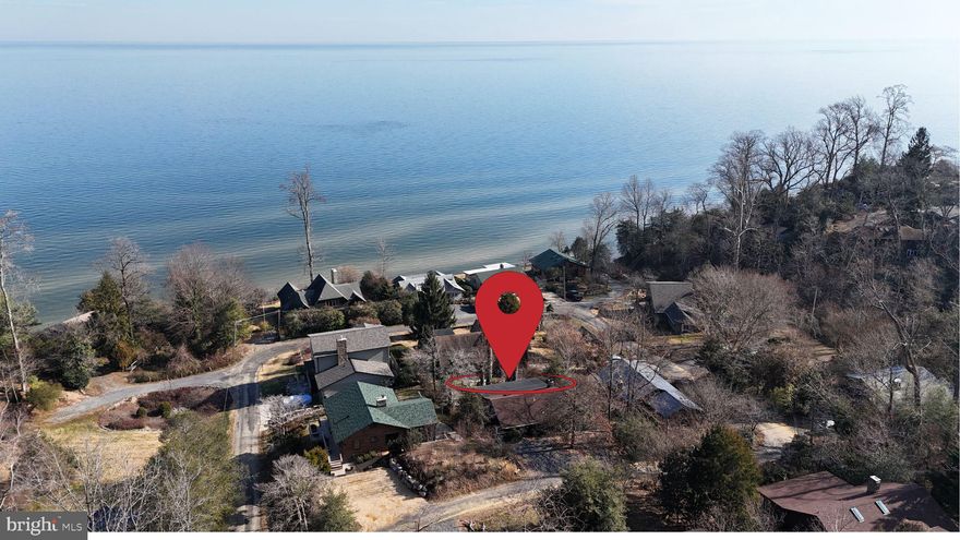 Tucked into the wooded shoreline community of Scientists’ Cliffs, this authentic log cabin blends craftsmanship, comfort, and Chesapeake Bay views. Built in 1956 and thoughtfully maintained, the home offers timeless character with meaningful updates that make it truly livable today.

The main level features post-and-beam construction, rich hardwood floors, and a striking stone fireplace that anchors the living space and creates instant warmth. Natural light filters through the cabin-style windows, connecting the interior and water views beyond. The layout includes three bedrooms and two full baths, with an updated bathroom that respects the home’s original character while adding modern function.

The finished lower level adds flexible living space, perfect for a family room, guest area, or home office, while still offering additional storage space. A porch and deck extend the living outdoors, ideal for morning coffee, evening dinners, or simply enjoying the quiet Bay breeze.

This home is being sold turn-key, making it easy to step right into the Scientists’ Cliffs lifestyle, whether as a full-time residence or a weekend retreat.
The property sits on a designated water-view lot. The home includes approximately 2,232 square feet total space, with a finished basement, and a single fireplace confirmed in the tax record.

Scientists’ Cliffs is one of Calvert County’s most distinctive private communities, known for its preserved natural setting and strong sense of place. Residents enjoy private Chesapeake Bay beach access, a community pool, tennis courts, and a community center, all woven into a landscape of wooded roads and dramatic Bay views.
Located in Port Republic, the community offers convenient access to Route 2 and Route 4, making commuting to Prince Frederick, Annapolis, Joint Base Andrews, and Washington, DC achievable while still feeling worlds away from daily noise.