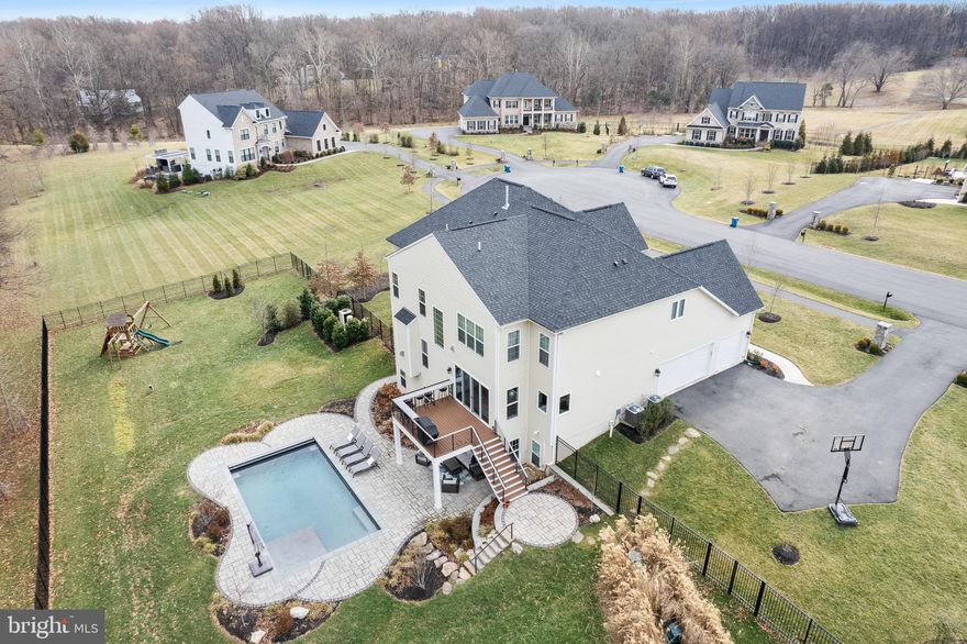 Welcome to 10259 Forest Lake Dr, a magnificent newly constructed estate in the esteemed Rivermont neighborhood. This exquisite, turnkey home, meticulously crafted by Basheer & Edgemoore, harmonizes timeless elegance with modern sophistication. It boasts an extraordinary backyard sanctuary and pool, five spacious bedrooms, eight bathrooms, a finished walk-out lower level, an expansive open floor plan, high-end finishes, and unparalleled craftsmanship situated on nearly 1.5 acres.

Constructed in 2020, this luxurious 3-level single-family home spans 6500 square feet. It features six generously sized bedrooms, two of which offer separate sitting and dressing areas, five full bathrooms, and three half bathrooms. The spacious interior boasts expansive 10-foot ceilings on the main level and 9-foot ceilings on the upper and lower level floors, creating an open, airy, yet stately ambiance.

The designer gourmet kitchen is a chef’s dream, equipped with Bosch stainless steel appliances, a large center island with ample storage, an additional breakfast bar, 42” custom cabinetry, and a spacious dining area. Sliding glass doors, framed by large windows, lead to a composite deck with built-in seating, perfect for informal al fresco dinners, overlooking the immaculately landscaped backyard and pool.

The elegant main level living spaces, including the living room, formal dining room, grand entry, and family room, are bathed in natural sunlight and feature solid hardwood floors. These versatile spaces are ideal for both formal and casual entertaining, as well as cozy everyday life. The main level also includes two powder rooms, an office, and a mudroom.

The upper level offers four en-suite bedrooms, including an elegant owner’s suite. This suite features two spacious walk-in closets, a grand sitting area, and a spa-like bath with a soaking tub, an oversized walk-in shower, and custom dual vanities. Across from the owner’s suite is a bonus bedroom/flex space, perfect for a guest room, additional office, nursery, art studio, hobby room or playroom. Laundry is also located on the upper level.

The sprawling, full daylight, walk-out lower level of this home offers an expansive, finished club room brimming with recreational and entertaining possibilities. A half bath conveniently located off the club room provides comfort and convenience for extended days and nights spent relaxing in the backyard pool.

The fifth en-suite bedroom on this level boasts a private full bath, a spacious closet, and a cozy reading nook, all with resort views overlooking the pool and patio. State-of-the-art (and new!) systems are conveniently located in the unfinished storage room, which is ready for the next owner’s creative vision. Consider adding a kitchen to the ensuite, a media room, or an exercise room.

The outdoor oasis boasts professionally landscaped grounds, a luxurious heated saltwater pool with a sun shelf, a playground, room for a private vegetable garden, and ample open spaces ideal for sports games and practices. Additionally, the property includes an expansive three-car garage and a whole-home generator.

Rivermont, one of Great Falls’ most sought-after communities, offers a serene yet convenient lifestyle, just minutes from popular schools, fine dining, shopping, and major commuter routes. This vibrant community comprises just nineteen homes, surrounded by a central pond and park, interconnecting trails, a wooded conservation area, and a distinctive tree-lined boulevard.