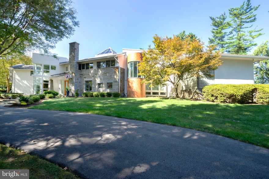 Offered to the public for the first time, this architecturally significant home will wow you around every corner! From the sweeping governor's driveway to the lovely flagstone entry porch, you are welcomed into this home through large double entry doors and you are immediately struck by the abundance of floor to ceiling windows flooding the home with natural light, while taking in the incredible lush perennial gardens and mature landscaping. The adjacent library with custom built-ins, secret passage, and two-story glass corner is just the start of this homes' well thought out openness and unique architectural touches. From the receiving room, enter the dramatic two-story family room with circular tray ceiling, hardwood floors and fireplace - perfect for intimate family gatherings and large-scale entertaining. This striking room also includes a sweeping main stair which floats under the large pyramid skylight - another unique feature that floods the home with natural light. Just off the family room is the game room and bar, with custom built-ins and gym. Rounding out the custom entertaining spaces in this home is a striking oval dining room with built-in storage, high ceilings and a wall of windows. The kitchen acts as a central hub, open and airy with center island, overlooking the sitting room/playroom complemented by a large pantry, ample storage, first floor laundry, adjoining breakfast area and a home office with walls of windows. The spiral staircase provides access to the kids' reading loft. Also tucked away on the first floor is the large guest suite with full bath. The second floor is the family retreat with two additional secondary bedrooms sharing a jack and jill bath, a third en suite bonus room and a large inviting owners suite with custom built-ins, fireplace, walk-in closet, dressing area and large marble bath. This custom home was designed with storage in mind, including ample closets and built-ins, and second floor storage room with access to the attic storage over the 3-car garage. The lower level is partially finished with playroom, media lounge with bar and powder room. The lovely rear flagstone terrace overlooks the large flat lot. Nestled in Flourtown's Country Club Estates, this central location offers easy access to shopping and transportation routes. The Green Ribbon walking trails and Fort Washington State Park are just steps away, with Valley Green, Forbidden Drive and Chestnut Hill just a short drive.