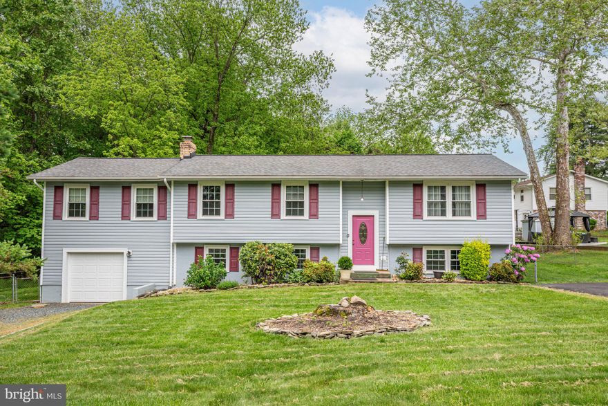 Prime North Stafford living with brand new carpet, completely freshly painted and plenty of wiggle room? Introducing 303 Austin Drive! This split-level abode has been under its long-time owners’ detailed care for many years. It includes four bedrooms and four baths and is on a .34-acre lot in the no-HOA Country Ridge community. The community is quietly tucked north of Route 610 less than 10 minutes west of I-95 (Route 610 exit)! With this location, there are tons of shopping, dining and grocery options right there along Route 610 and you’re within a 20-minute drive of Quantico. Downtown Fredericksburg and all its pizzazz is approximately 20 minutes south as well. Heading to the homesite, you’ll notice two driveways – one asphalt and one gravel. At the culmination of the gravel driveway is a lovely one-car garage that may easily serve as a workshop/man cave, too! The acreage has been nicely cared for through the years, now with a mix of delicate pops of low-maintenance landscaping and stately shrubs/trees. Note that there is a nice empty buffer on one side of the residence for added tranquility. Out back is a deck, fencing and the owners touched up/cleaned out the space last summer – there is plenty of space for the garden of your dreams! The home is blue with red shutters and boasts a split-level layout. The roof was updated in 2017! Inside and heading up to the main level, you’re greeted with the living room with built-ins. New carpet flows throughout the majority of this level! The nearby kitchen includes medium wood cabinets and stainless-steel appliances – it is very much an open country kitchen vibe, and you can access the deck right off it. Down a hall, you’ll find a small bedroom that is currently leveraged as an office – there’s a full bath across from it. Continuing, there is a bedroom with an ensuite bath (shower and single sink). What once was another bedroom has been totally morphed into a sitting room adjacent to the primary bedroom! The primary suite, now over the garage, includes hardwood floors, a walk-in closet and ensuite bath with a tub/shower combo. Heading to the lower level, it includes a central living room, a bedroom, full bath (shower set-up) and unfinished laundry room. There is a bonus room with shelving to make all your own! Systems-wise, the residence is served by two heat pumps and the hot water heater was replaced within the last year. The current owners love the residence because “it’s roomy, there is room for privacy and, for residents and guests, everyone can have their own bathroom.” Convenient and spacious, 303 Austin Drive is ready for you and yours!