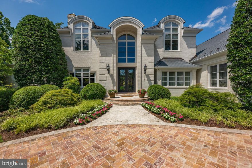 A grand presence in the heart of Bethesda. This stately residence offers over 7,000 square feet of refined living space, set behind a sweeping stone driveway with a roundabout approach, an attached 3-car garage, pool with hot tub and lush professional landscaping surrounding the entire property. Enter through elegant double glass doors into a soaring two-story foyer, where a dramatic curved staircase with detailed ironwork sets the tone for the sophistication found throughout the home. Designed for both gracious entertaining and everyday comfort. The main level features the expansive primary suite, which is a true retreat. An oversized bedroom with vaulted ceilings, French doors that open to an idyllic private terrace, a custom walk-in closet, a spa-inspired bath with soaking tub, oversized glass shower, dual vanities, and exquisite stone finishes. Adjacent to the primary suite is a richly paneled library/office. The main level also features a formal living room with a fireplace, spacious dining room with butler’s pantry, and a sunlit family room anchored by a floor-to-ceiling stone fireplace. At the heart of the home, the gourmet kitchen impresses with tall ceilings, walls of windows, and top-of-the-line appliances including a Sub-Zero refrigerator, Wolf double wall ovens as well as a professional-grade Wolf six-burner gas range with pot filler. A generous center island with bar seating completes the space. Upstairs, 3 additional en-suite bedrooms offer comfort and privacy for family and guests. The finished walk-out lower level is designed for both entertaining and everyday living, featuring a spacious recreation room with fireplace and half bathroom, a beautifully crafted wood-paneled bar, a dedicated gym area with a mirrored wall, additional room ideal for a home theater and a guest bedroom/au-pair suite with doors to the outside. Outside, the backyard unfolds like a private resort, with mature trees, an expansive stone patio, built-in gas grill, and serene views of the pool and spa—perfect for al fresco dining and outdoor entertaining. This exceptional residence offers privacy, timeless architecture, and modern luxury—just minutes from Bethesda Country Club, Congressional Country Club, Burning Tree Club, and other premier local amenities. Located in the Walt Whitman School Cluster. *Please note: Square footage is estimated and calculated by an independent third party; information is deemed accurate but not guaranteed.