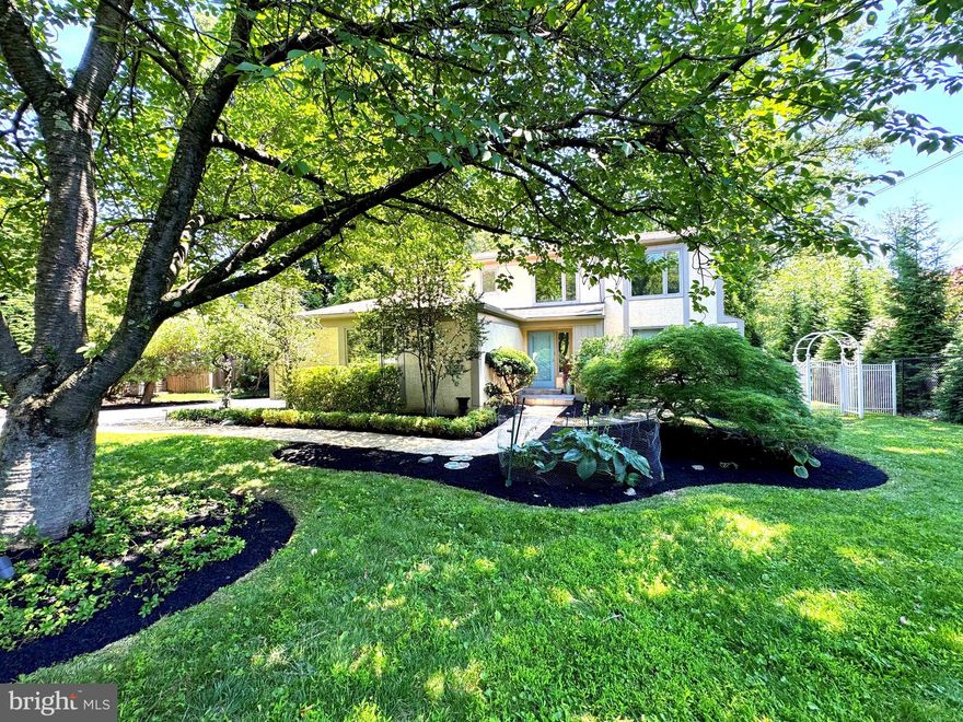 Set well back from the road on a lush, flat 0.5-acre lot, this striking 4-bedroom contemporary residence blends custom design, quality craftsmanship & elegant modern living in one of Penn Valley’s most desirable locations.
A circular driveway welcomes you to a two-car garage & a winding brick paver walkway that leads to the front door. Inside, the gracious marble-floored center hall sets the tone with a large coat closet & an open, balconied staircase leading to the second floor.
The sun-filled living room features hardwood floors, a large picture window & distinctive architectural see-through walls creating visual continuity & modern flair. The adjacent family room is a warm, sophisticated gathering space with hardwood floors, a honed marble fireplace & custom, handcrafted walnut cabinetry, including a matching wet bar. French doors with sidelights open to a terracotta-tiled, awning-covered patio that overlooks the expansive, private rear yard, ideal for relaxing or entertaining.
The spacious formal dining room offers marble floors & three large windows with front & side views. The bright kitchen features a picture window overlooking the gardens, white cabinetry, granite countertops & top-tier appliances including a Wolf gas range, Best exhaust hood, GE Monogram built-in refrigerator, dishwasher & a wine rack. The adjoining breakfast area offers space for a large table, additional views of the backyard & offers a connecting full laundry room with patio access.  From the hallway, there is a guest powder room with mirrored wall & custom wall sconces, completing the main level.
Upstairs, a vaulted ceiling & open balconied hallway add volume & light. The primary suite features French doors with a Juliet balcony, a wall of custom Italian Poliform built-in storage cabinets & a private dressing room with built-in vanity, walk-in closet & access to a luxurious Carrara marble bath with oversized shower, double windows, large vanity & custom cabinetry.
Three additional bedrooms are spacious & bright, with ample closet space. A beautifully finished hall bath includes custom tile, built-in cabinetry, pedestal sink, large tub/shower & stylish finishes.
The finished lower level boasts flexible space for recreation, fitness, work, or guests. It includes a game room, large, shelved closet, under-stair storage, a mirrored exercise area, an office with cedar closet & a full bathroom. There is also a large unfinished area perfect for storage & utilities.
This thoughtfully designed home offers privacy, light & architectural interest just minutes from top-rated Lower Merion schools, Center City &  all the best of the Main Line!