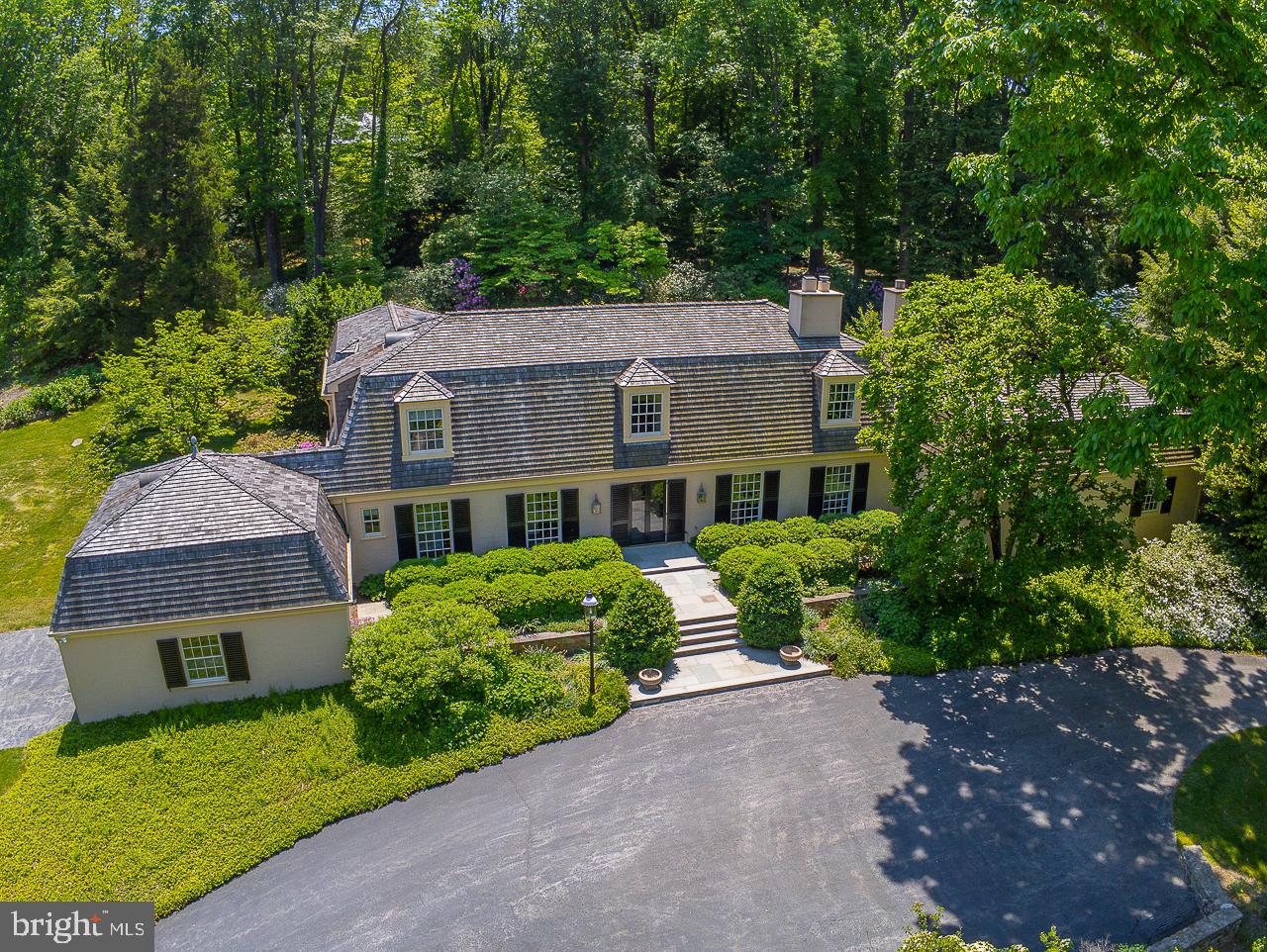 Tucked along a private lane, on one of the most coveted streets on the Main Line, sits 237 Atlee Road. A semi-circular driveway and a grand stone entry welcome you to this spectacular property with superb craftsmanship, exceptional attention to detail, and sprawling lush gardens. The grand entry hall is a gallery of refined architectural details, with soaring windows, curated art lighting, and an elegant expert milled staircase. The foyer leads to the main living spaces and luxurious master suite, all with stunning views of the gardens, stone patio, garden pool and woodland garden; the perfect backdrop for time spent with family as well as formal gatherings. The custom designed gourmet kitchen is a chef’s dream and opens to the grand family room with gorgeous coffered ceiling and sweeping views. A fabulous butler’s pantry with mahogany and brass accents adjoins the formal dining room and living room. The well-appointed master suite is on the main level with an adjoining sunroom/office overlooking the garden pool. It features hardwood floors, a charming wood-burning fireplace, a dressing room with solid Cherry wardrobes, and a luxurious marble ensuite bath with solid Cherry vanities, stall shower, soaking tub and radiant heat floors. The upper level has an office and three additional bedrooms, two bedrooms with a Jack and Jill bath, and a fourth bedroom with an ensuite bath. The lower level is partially finished with a half bath and additional storage, and offers plenty of room for expansion.