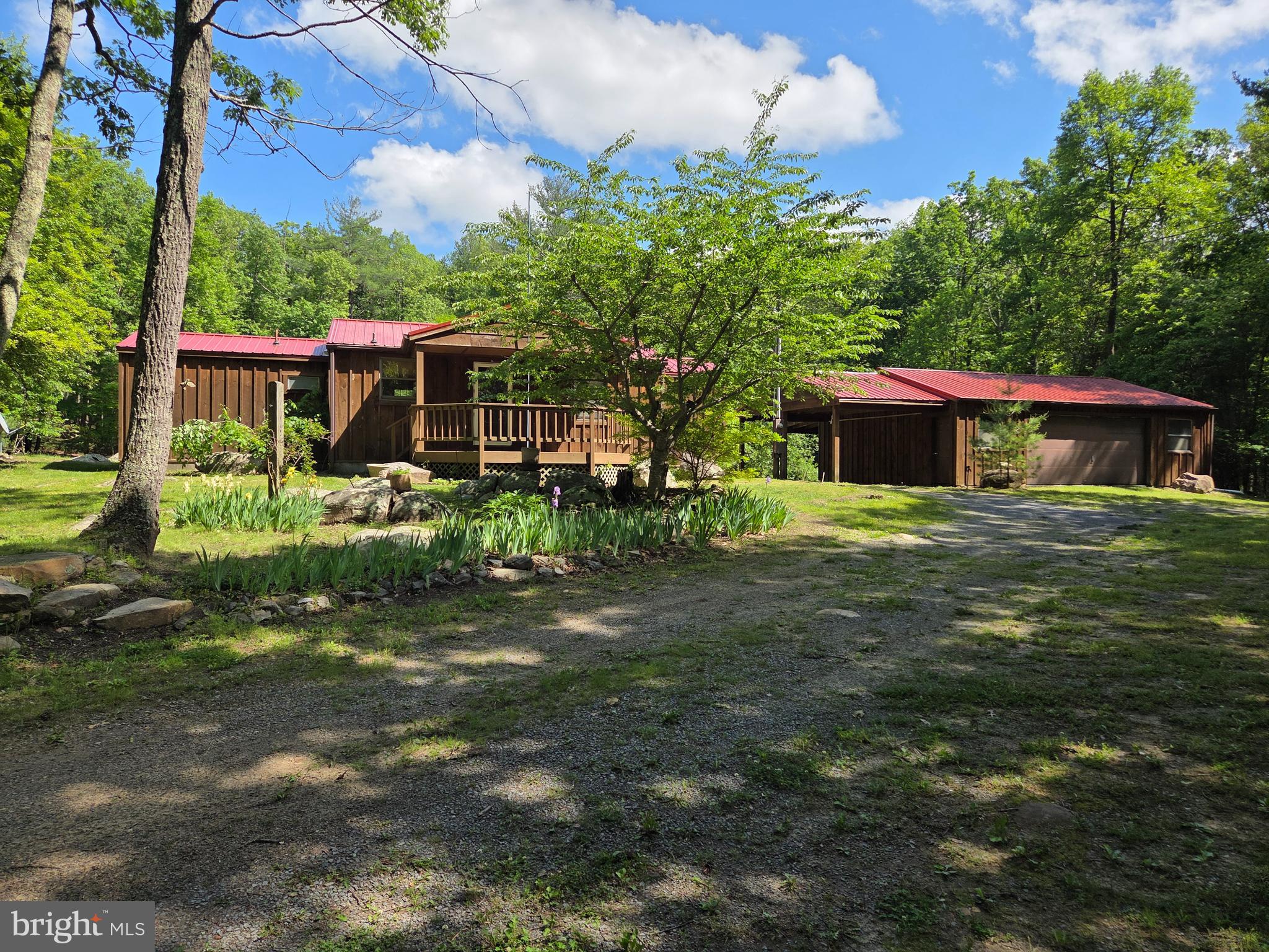 PARK-LIKE SETTING!!! Once a singlewide manufactured home converted to a very cozy getaway cabin with wood laminate flooring and a spacious living room area. Front porch deck overlooks beautiful natural landscaping and circular driveway leading up to the cabin. Gorgeous open rear yard with sporadic placed trees and "natural rock outcroppings"...fire pit too for relaxing evenings! Wait there's more... a detached 2 car garage with attached carport! Just five miles outside of Capon Bridge...Secure your weekend getaway!