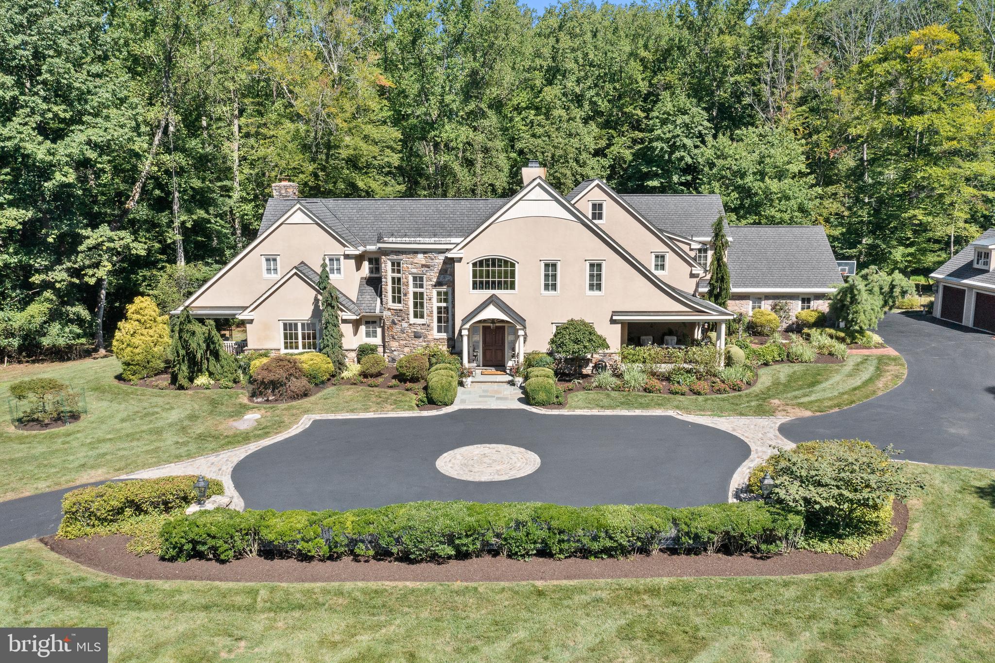 Privacy, luxury, and spacious living all come together to make 370 Dutton Mill Road a spectacular home. In its first listing ever, this architectural masterpiece constructed by renowned builder Ken Casella & Assoc. is situated on 9 private acres in the prestigious Radnor Hunt community in Willistown township, and offers the best living the Main Line has to offer. With an abundance of comfortable design throughout this wonderfully maintained home, this tranquil property has an abundance of outdoor space that is sure to impress with multiple porches, a large flagstone patio with adjoined fire pit. Walk over the stream, on a custom constructed bridge, to the private tennis court. The multi-access driveway with paved motor court welcomes you to the property displaying immense curb appeal with lush, mature landscaping. Inside, the open and airy foyer sets the tone for the rest of the home. Pristine American Cherry hardwood floors and plenty of windows are glittered throughout, drenching the home with warm natural light.
To the right as you enter, you will find the ample dining room that opens into the fully equipped kitchen.
This masterful kitchen and breakfast area offers two islands, gorgeous granite countertops, plenty of crisp white cabinetry, high-end stainless-steel appliances, and a gas fireplace to warm yourself while you sip your coffee during the fall and winter mornings.
Next is the family room which is complete with built-in shelving and a stylish coffered ceiling. Close by, the formal living room features a gas fireplace and french doors that lead to its own flagstone patio. An elegant study adorned with more built-in shelving has its own private porch where you can work and enjoy the privacy in your down time.
Conveniently next to the kitchen is a sun-washed second office, providing ample space for both work and leisure. Adjacent to a spacious laundry room and a mudroom leading to the attached garage lies the first-floor primary suite. With two walk-in closets and spa quality bathroom with double sink, an extensive glass-enclosed shower, and a whirlpool/soaking tub offers you your own private oasis. The first floor is conveniently complete with two powder rooms. Upstairs you will find the 4 additional well-sized bedrooms, two of which share a jack-and-jill-style bathroom. The following 2 include their own ensuite bathrooms, one with an attached bonus studio gives the feeling of a private second floor guest suite.
Additionally, the second-floor includes a den with a large walk-in storage closet and full laundry space. The lower level of the home is fully equipped with a theater, billiard room, wet bar, ice-maker, temperature-controlled wine cellar, yoga studio with sauna, fitness gym, and a full bathroom. All of which can easily access the grand outdoor patio space through its own walk-out entrance.
An additional 3 car garage located at the upper end of the property, is makes an excellent space for additional storage, specialty vehicles or seasonal equipment and tools.
370 Dutton Mill is ideally situated minutes away from desirable shopping and dining destinations, highly ranked schools, as well as the Amtrak Train station, providing everything your family could want or need. This exclusive home is distinguished by its quality indoor living spaces, open and airy floor plan, an abundance of outdoor retreats, and supreme location. All of which combine to make this the dream home for its future owners.