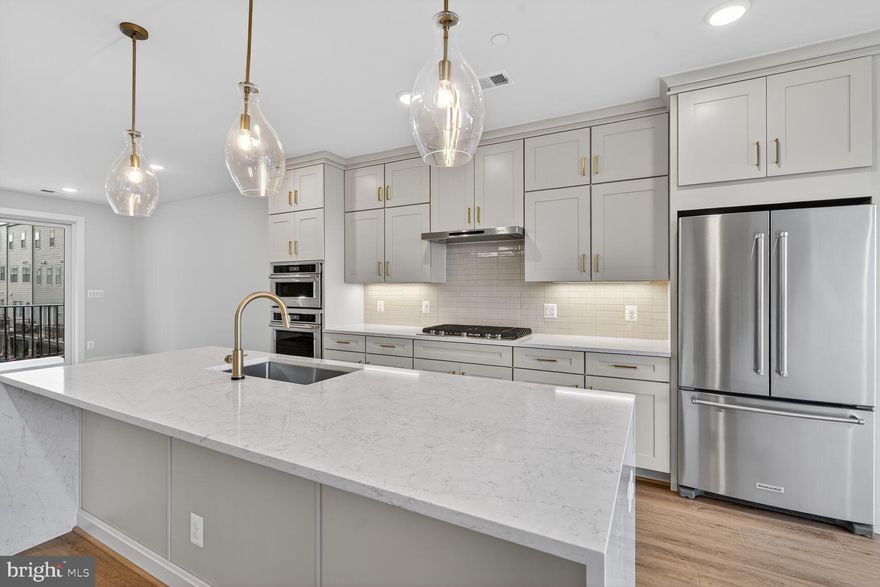 This two-level penthouse condo features an open and airy main level with a gourmet kitchen, light-filled dining room, pocket office, and spacious great room that flows seamlessly to the outdoor living space. The kitchen is complete with Pearl Jasmine quartz countertops, waterfall island, Artisan Maple Agreeable Gray cabinets, KitchenAid stainless steel appliances, and gold hardware. Upstairs you’ll find a luxe primary suite with two walk-in closets, two secondary bedrooms, and a full laundry room.