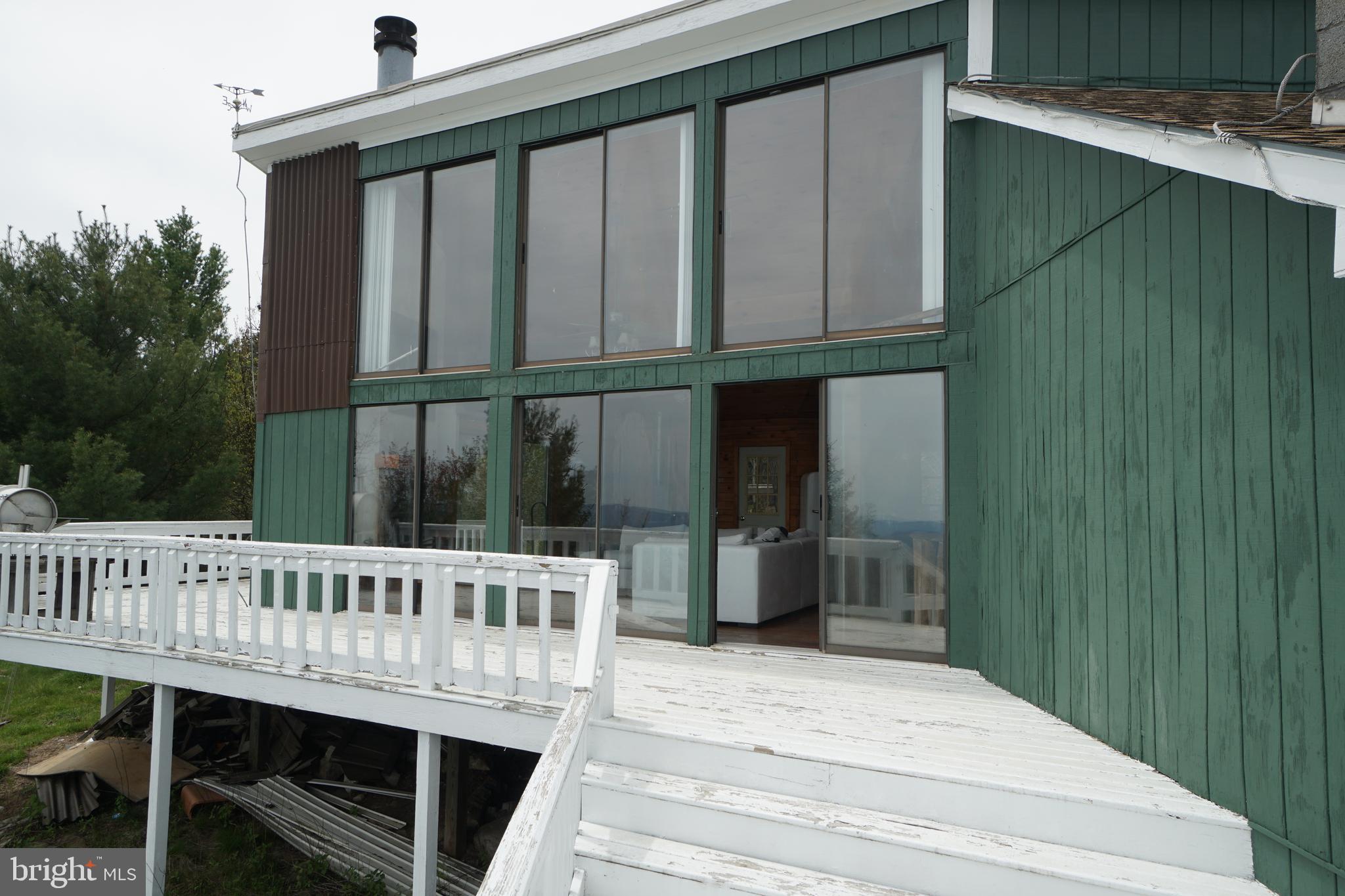 Spectacular Views from this mountain top cabin! Come and relax at birds eye view on the spacious deck. The wood ceiling/walls in the interior invites you to sit and unwind in the warmth and coziness of the cabin. The cabin has and on site septic, propane/wood heat. Propane also fuels light fixtures and cooking stove. Water is cistern water from rain water collection. The outbuilding on property stores the generator which is hard wired to the cabin for ease of use. Shingle roof installed new in 2020. Some restrictions apply. No HOA, only Property Owners Association.