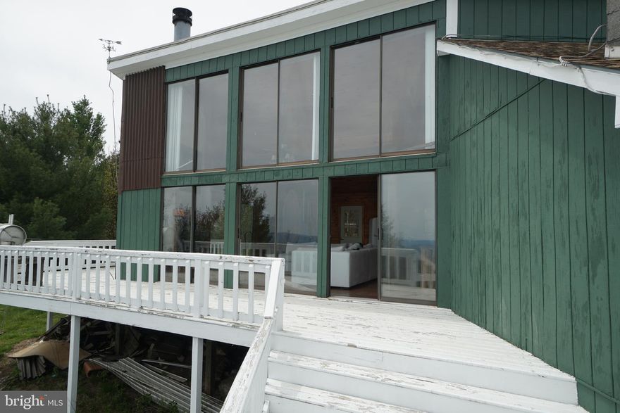 Spectacular Views from this mountain top cabin! Come and relax at birds eye view on the spacious deck.  The wood ceiling/walls in the interior invites you to sit and unwind in the warmth and coziness of the cabin. The cabin  has and on site septic, propane/wood heat. Propane also fuels light fixtures and cooking stove. Water is cistern water from rain water collection. The outbuilding on property stores the generator which is hard wired to the cabin for ease of use. Shingle roof installed new in 2020. Some restrictions apply. No HOA, only Property Owners Association.