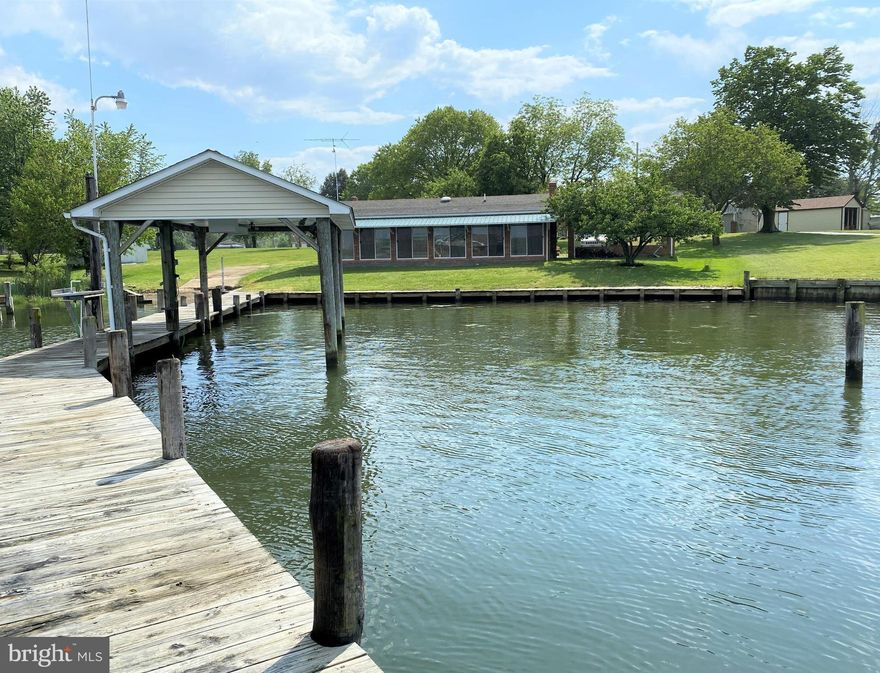 YOUR OWN PRIVATE BOAT RAMP on deep protected water comes with this spectacular waterfront property on 1 Acre. Enjoy views, boating and water sports from your own private dock with a drydock boathouse that has an electric boat lift. You can clean your  catch of the day  in the convenient stainless-steel sink/counter (with running water) right on the 5 foot wide dock! Also, you will enjoy crab feasts on your large sunporch/Florida room that runs the entire length of the house facing the water. Great views!! Water frontage is around 100  feet of shoreline  that is all bulk-headed with a 3 foot wide boardwalk on top. There is deep water right at the end of the dock -  easy for bringing boats in. This home has a great layout for entertaining guests. The kitchen has beautiful Poplar wood cabinets and plenty of storage. There is a wood stove on a brick hearth for those chilly evenings, and a large living room. The house has plenty of natural light throughout. This 1780 square foot home with open concept floor plan features spacious bedrooms. All the bedrooms have ceiling fans and the hall bath has a deep garden soaking tub with shower. Master bath features large ceramic tile shower with seat bench and double sprayers. There are pull-down stairs for the attic storage space. The electric heat is controlled in each room as needed and there are good cross breezes if you like fresh air or the window air conditioner supplies AC to the house nicely.  There is  also a duct line that runs the length of the house. This solidly built home is masonry built with siding over it. The house needs a little cosmetic TLC (a little bit dated interior), but it is clean and can easily be lived in as you re-do it, a little at a time.  Also comes with a great Amish built shed (approx. 18 ftx12 ft) with a ramp and plenty of storage shelves. It also has electricity, windows, ceiling fan and a workbench in it. Being at the end of the road, it is quite private with no through traffic.  You will not  want to miss this amazing opportunity to own your little paradise on the water. It is an easy commute to PAX River NAS and only a little over an hour from Washington DC and National Harbor!