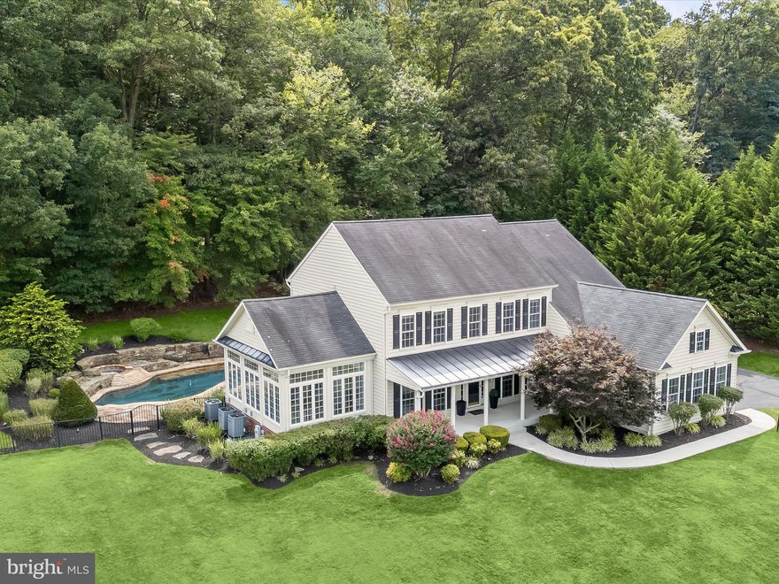 Experience refined living in this five bedroom, three-and-a-half-bathroom home, set on a serene 1.12-acre lot backing to lush trees. Designed for both relaxation and entertaining, this property features a custom in-ground pool with hot tub, expansive stone patio, and built-in BBQ outside. A long private drive leads to the impressive exterior, where a covered front porch offers an inviting spot to enjoy peaceful mornings or evening views. Step inside to a grand two-story foyer filled with natural light, complemented by freshly painted walls. Hardwood floors and accent trim moldings grace most of the main level with a living room and formal dining room that create elegant spaces for gatherings. Unwind in the sunroom that boasts a soaring tray ceiling and three walls of windows that capture panoramic views of the surroundings. Prepare your favorite meals in the kitchen equipped with granite countertops, stone backsplash, 42-inch cabinetry, pantry, and center island with breakfast bar. Stainless steel appliances include a gas cooktop and double wall oven. Off the kitchen, a breakfast room with a cathedral ceiling invites casual dining while the family room is anchored by a cozy gas fireplace. French doors open to a main level office for a quiet workspace, and a powder room, laundry room, and access to the three-car complete this level. Upstairs, the primary bedroom awaits with a tray ceiling, two walk-in closets, and an ensuite bathroom with dual vanities, a walk-in shower, soaking tub, and private water closet. Down the hall, three additional bedrooms share a renovated full bathroom with a tub-shower featuring jetted body sprayers. The finished lower level adds exceptional versatility with a massive recreation room, wet bar, and bonus room with built-ins. Perfect for guests, the fifth bedroom on this level has a separate walk-out entrance outside and an adjacent full bathroom. Outdoors, the resort-style pool and hot tub are surrounded by a custom stone patio, perfect for gatherings, relaxation, and enjoying the tranquil wooded backdrop. Some images have been virtually staged.