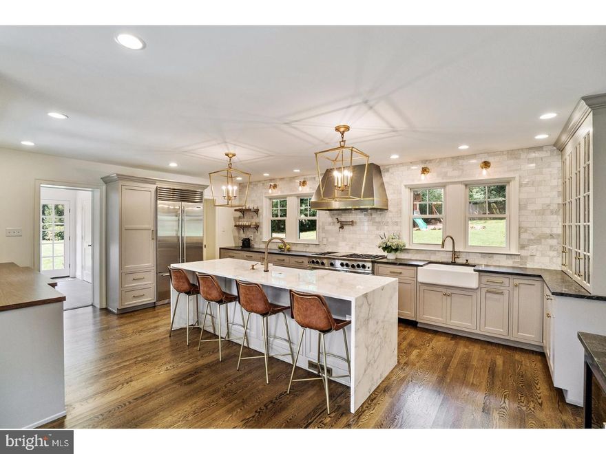 A two-story addition by Architect Warren Claytor transformed this home into a sanctuary nestled on 1.15 quiet and secluded acres with mature trees and beautiful landscaping on a highly desirable Cul-De-Sac street in Wayne, Pa. Meticulously updated and renovated with the finest materials and finishes, this home features 7 bedrooms, 3 full bathrooms and 2 powder rooms and 4385 Square feet. A bonus room with vaulted ceilings above the two garage can be converted into an artist studio or media/game room. Natural light fills this stately center hall home and warm hardwood flooring is accented by original millwork. At the North end of the home is a family/living room complete with fireplace and two sets of French doors that open to the large covered porch and side yard. At the middle of the first floor is a formal dining room with views of the large front yard, sconce lighting and chandelier. Just off the back of the dining room is a hallway with vintage built in buffet cabinet, coat closet and back staircase. At the South end of the house is a glorious designer eat in kitchen with breakfast area, large island with Calcutta marble waterfall countertop, large walk in pantry, professional 48" blue star gas range with dual oven, custom hood, built in subzero refrigerator and wine fridge. Kitchen finishes also include custom wood cabinetry with soft close doors, drawers and slide out storage drawers and farmhouse sink. The feature wall is tiled in marble subway tiles and highlighted by designer lighting in brushed brass. Beyond the kitchen is the mudroom entrance with built in cabinets for coats and shoes. This area also includes a powder room. The 2nd level includes 4 bedrooms including the stunning master suite with ensuite bathroom and walk-in closet with island dresser. The designer master bathroom features two large vanity cabinets in gray, marble tiled floors, large walk in marble tiled shower and separate water closet.  A Jack and Jill bathroom serves two bedrooms on this level. The 3rd bedroom is used as a yoga studio while the 4th bedroom is currently set up as a sitting/play room. The 3rd level features 3 more bedrooms, one guest room, one currently used as an office and the last one set up as a music room. The home also uses Geothermal energy for heat and AC. This home is in Radnor Township School District. It's very close to Wayne Village and offers easy access to 476, King of Prussia and Center City. Schedule a tour today and get ready to fall in love.