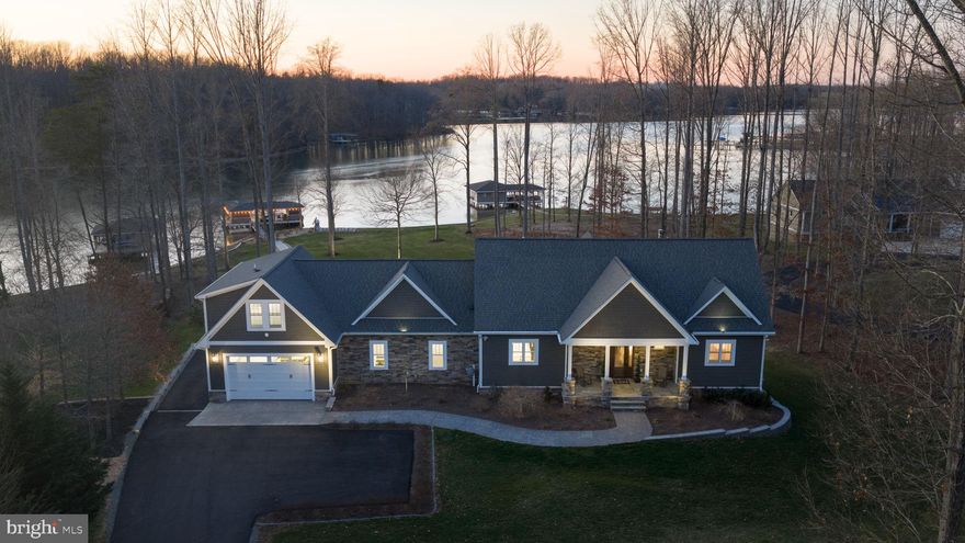 Extraordinary fully-furnished waterfront estate, perfectly set on the tranquil private side of Lake Anna, offering an unmatched blend of luxury, custom craftsmanship, and breathtaking natural beauty, along with high-speed fiber internet.  With 140+ feet of pristine shoreline and sweeping, unobstructed water views, this waterfront property presents a rare opportunity to experience a refined lake life.  Encompassing more than 5,600 square feet of thoughtfully designed living space, this home features seven generously proportioned bedrooms, including five private en-suite retreats, ensuring exceptional comfort and privacy.  Craftsman-inspired architecture is showcased throughout, highlighted by rich hardwood flooring, extensive custom trim work, chair rail, and other refined finishes.  The great room features soaring vaulted ceilings, custom built-in bookcases and shelving that frame an elegant fireplace crowned with a beautiful white mantle and stone work.  The large four-seasons room is encased by massive windows showcasing incredible views of the lake.  The expansive gourmet kitchen is designed for both entertaining and everyday living, featuring premium stainless steel appliances, a massive island graced by pendant lighting, a double wall oven, large gas cooktop, a built-in ice maker, beverage refrigerator, and an impressive walk-in pantry adorned with elaborate custom shelving.  The second floor offers two spacious primary suites, each with clear lake views, en suite bathrooms, and large walk-in closets.  The finished lower level further elevates the home’s entertaining capabilities with three additional bedrooms (one with a true functioning Murphy bed!), and a full-scale wet bar / kitchen with stainless appliances and custom stone work, creating an ideal space for gatherings and recreation.  Outdoors, the estate transforms into a private lakeside sanctuary set on a perfect flat lot showcasing incredible water views.  The custom-designed boathouse is a showpiece in itself, complete with a luxurious kitchenette, a vibrant tiki bar with roll-up windows, elegant granite countertops, a dedicated storage room, and a boat slip equipped with an electric lift. A sandy beach, a massive inviting hot tub, and expansive stone fire pit area with an abundance of outdoor furniture create the perfect setting for relaxation and unforgettable evenings along the water.  Adding both versatility and distinction, the property includes a completely finished attached garage with recessed lighting, built-in workspaces, cabinetry, and an extensive private primary suite above, offering exceptional space for guests, extended family, or creative use.  Surrounding the residence, meticulously curated landscaping and hardscaping wrap the property with breathtaking beauty, complementing the serene waterfront backdrop.  A 17-zone irrigation system keeps the landscaping fresh and hydrated.   Great location: close to groceries, restaurants, fast food, ABC, and more. This remarkable Lake Anna escape offers a rare convergence of elegance, privacy, and resort-style living, where every detail has been thoughtfully designed to deliver a truly exceptional waterfront lifestyle.  INVESTORS: short term rentals are permitted in this subdivision.  Lake Anna has been rated one of the top short term rental locations in the entire nation, and is home to some of the top-performing short term rentals in the Commonwealth of Virginia.  Purchase includes furniture, furnishings, decorations, appliances, and elevated lifestyle.